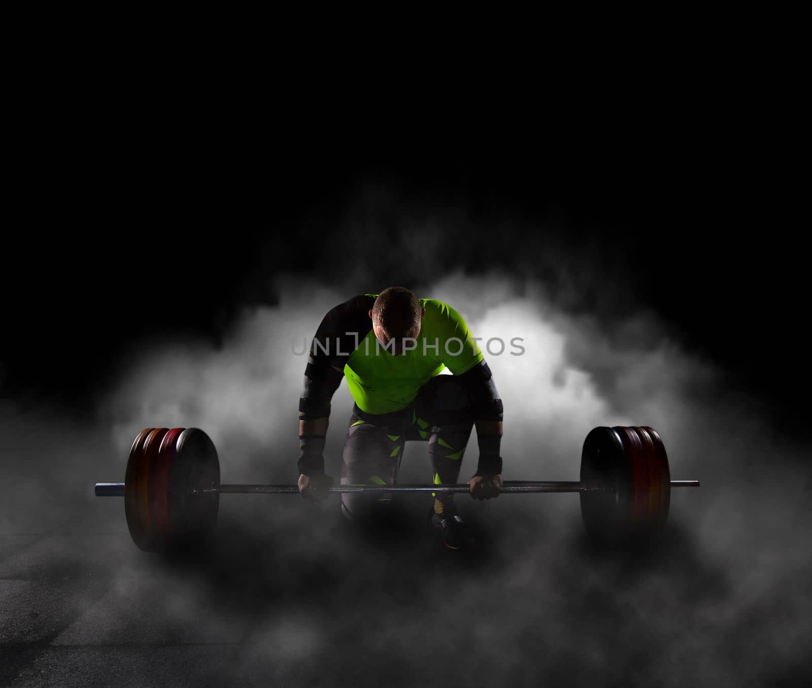 guy athlete bodybuilding goes in for sports in the gym lifts the barbell from the floor concentrated and confident with both hands heavy weight and strong guy fitness creative photo. High quality photo