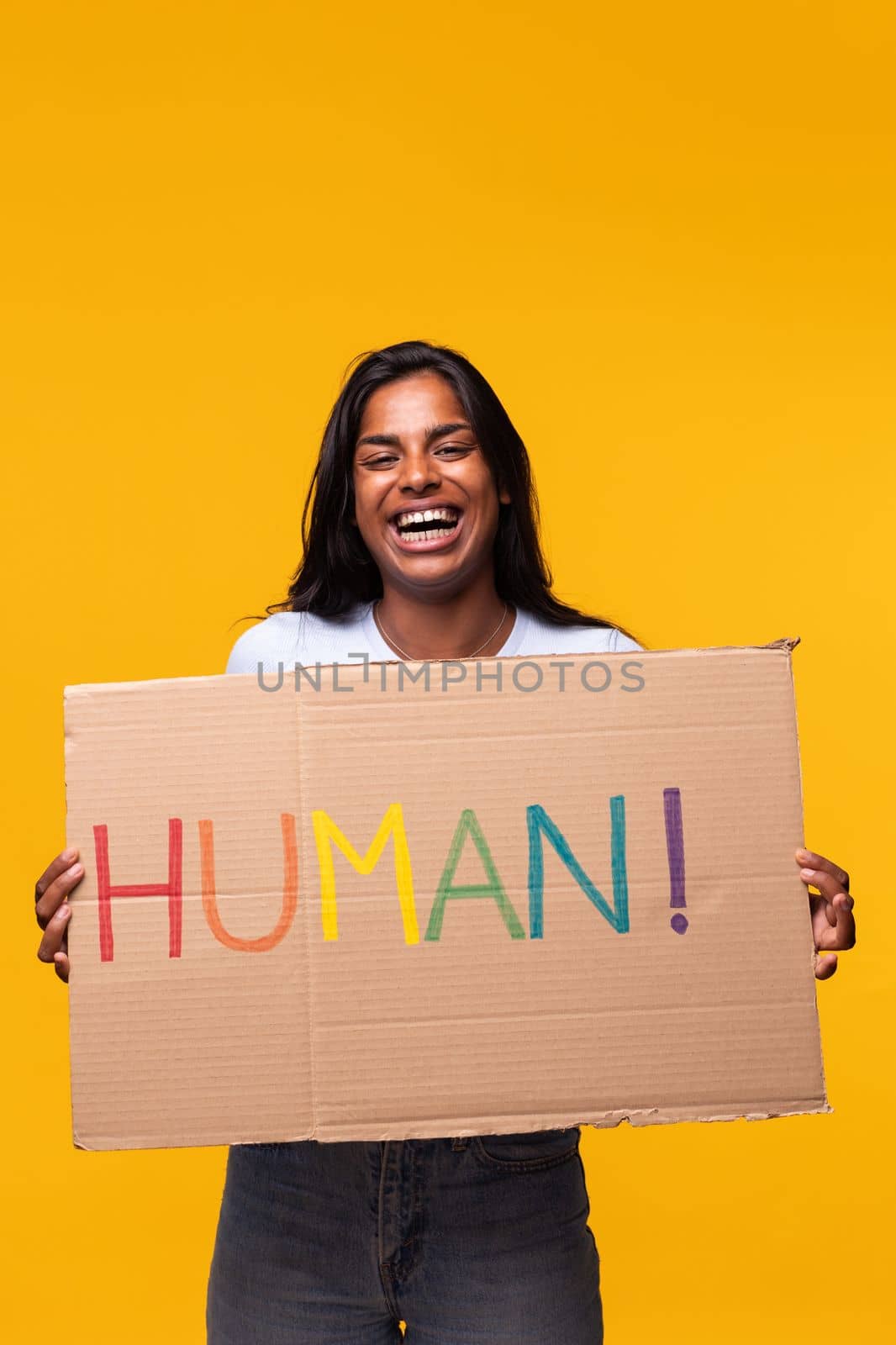Portrait of young indian woman holding a LGTB rights cardboard poster isolated on yellow background.Studio shot. by Hoverstock