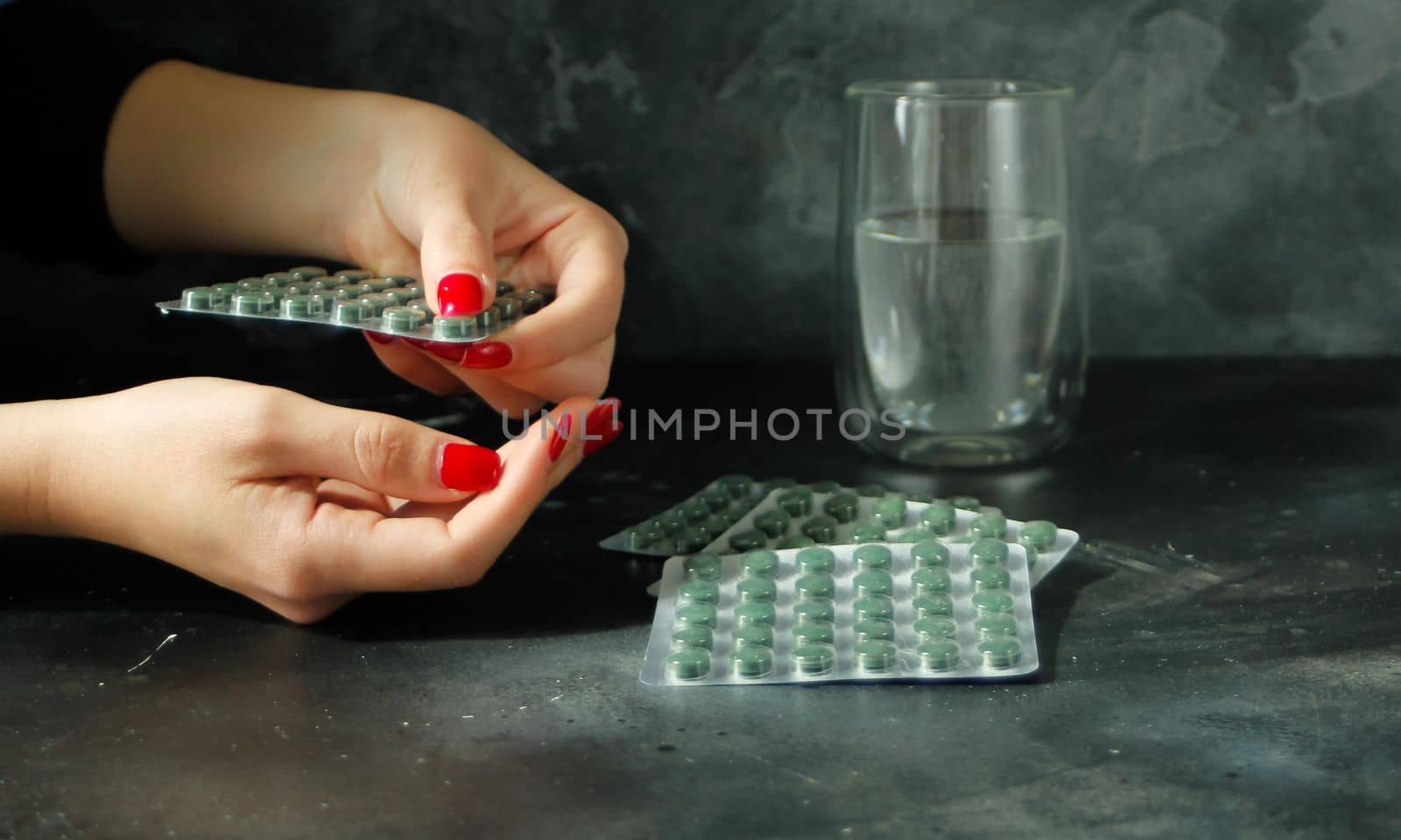 Woman hand taking spirulina tablet by danjelaruci