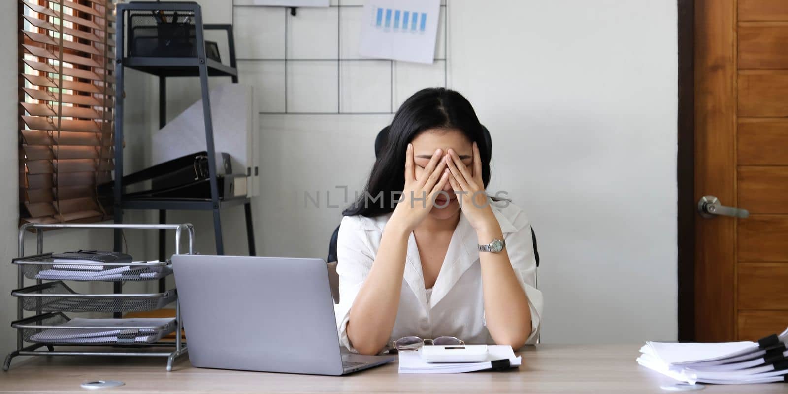 Tired female employee holding head on hand, looking at computer screen, doing hard task, having problem with computer software. Stressed exhausted businesswoman suffering from headache, feeling bored