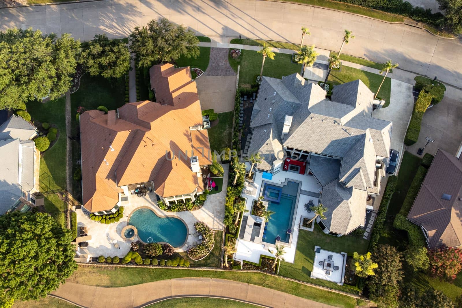 Aerial view of mansions with swimming pools surrounded by green grass and trees in the summertime. by Khosro1