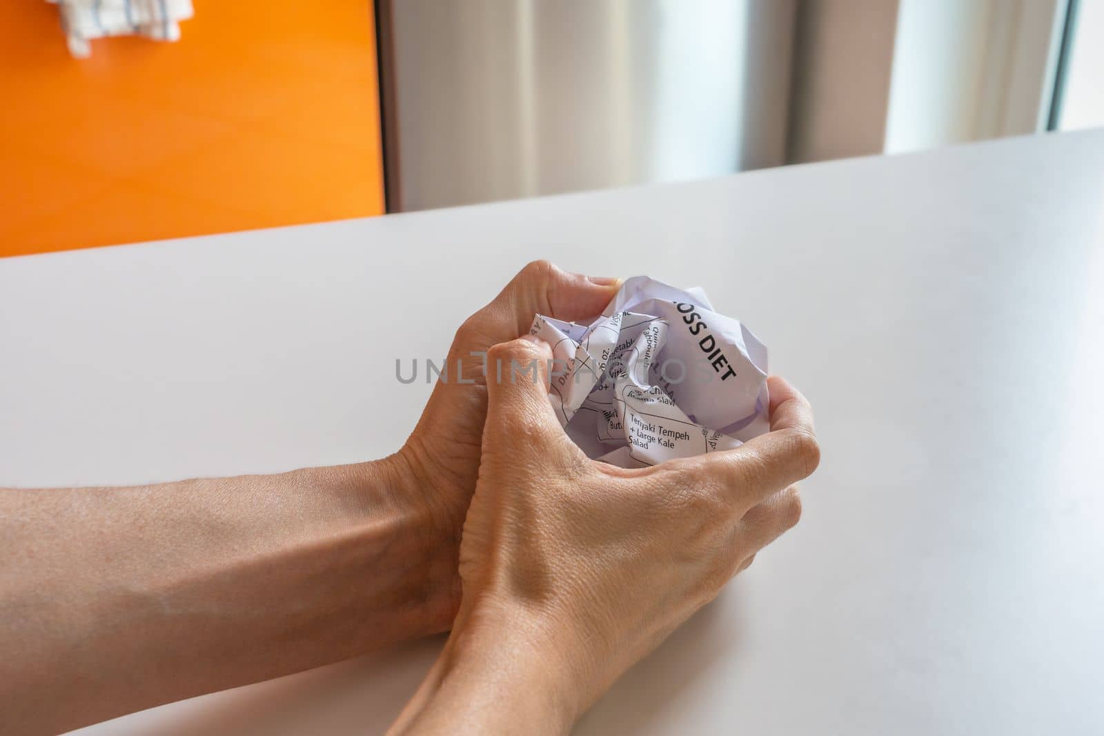 Two hands holding a crumpled sheet of paper with diet.