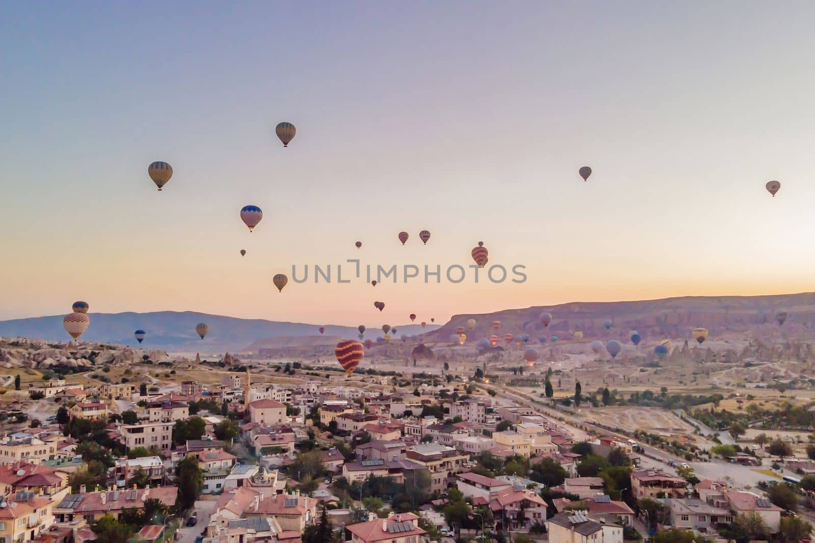 Colorful hot air balloons flying over at fairy chimneys valley in Nevsehir, Goreme, Cappadocia Turkey. Spectacular panoramic drone view of the underground city and ballooning tourism. High quality by galitskaya