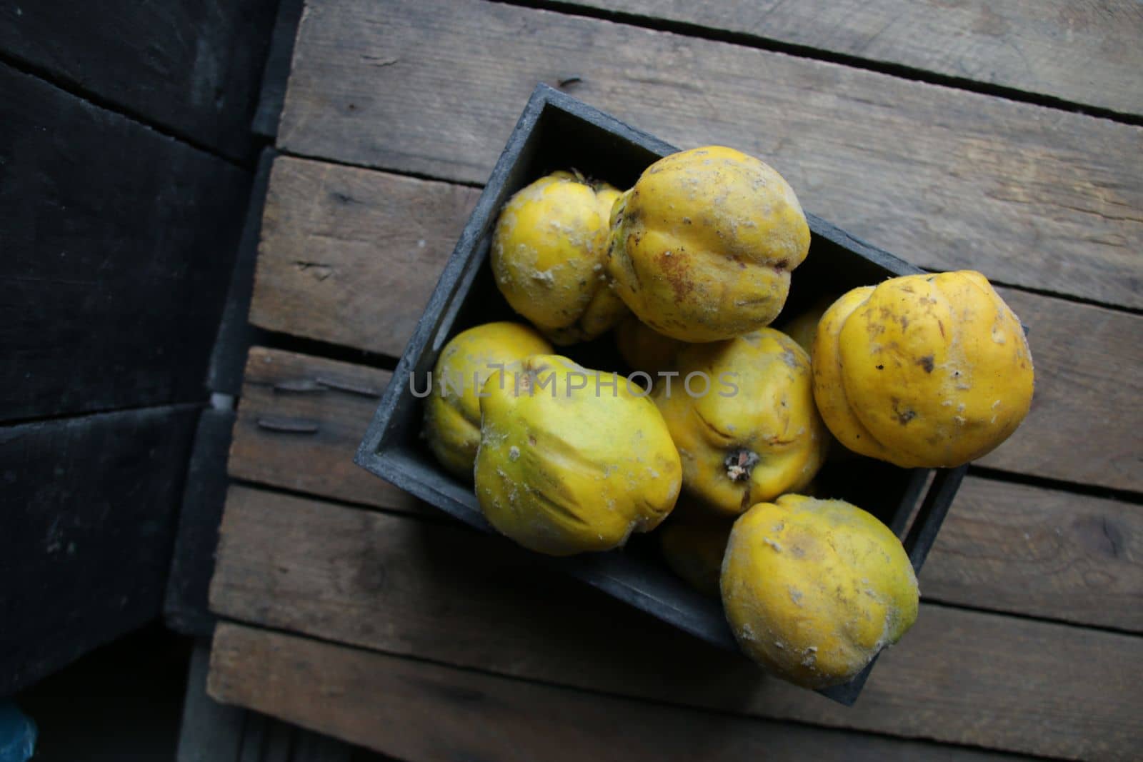 Ripe quince in a box on a vintage wooden table.