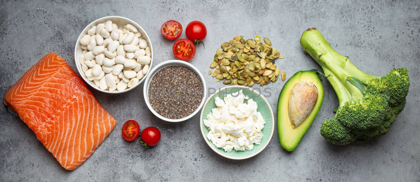 Selection of healthy food products if a person have diabetes: salmon fish, broccoli, avocado, beans, vegetables, seeds on grey background from above. Healthy diabetes diet