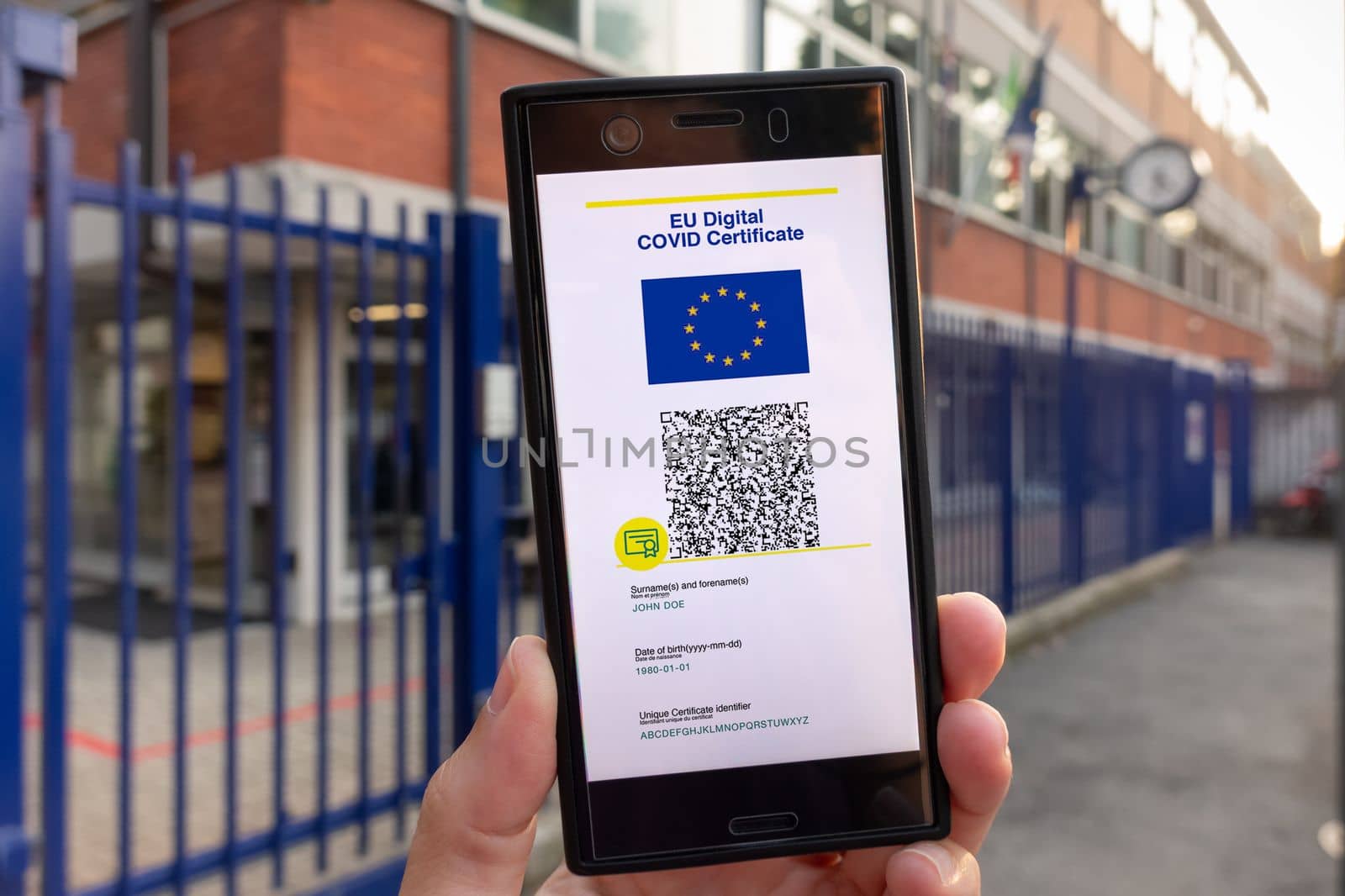 Woman showing on smartphone EU Digital Covid Certificate Green Pass with quad code. School background.