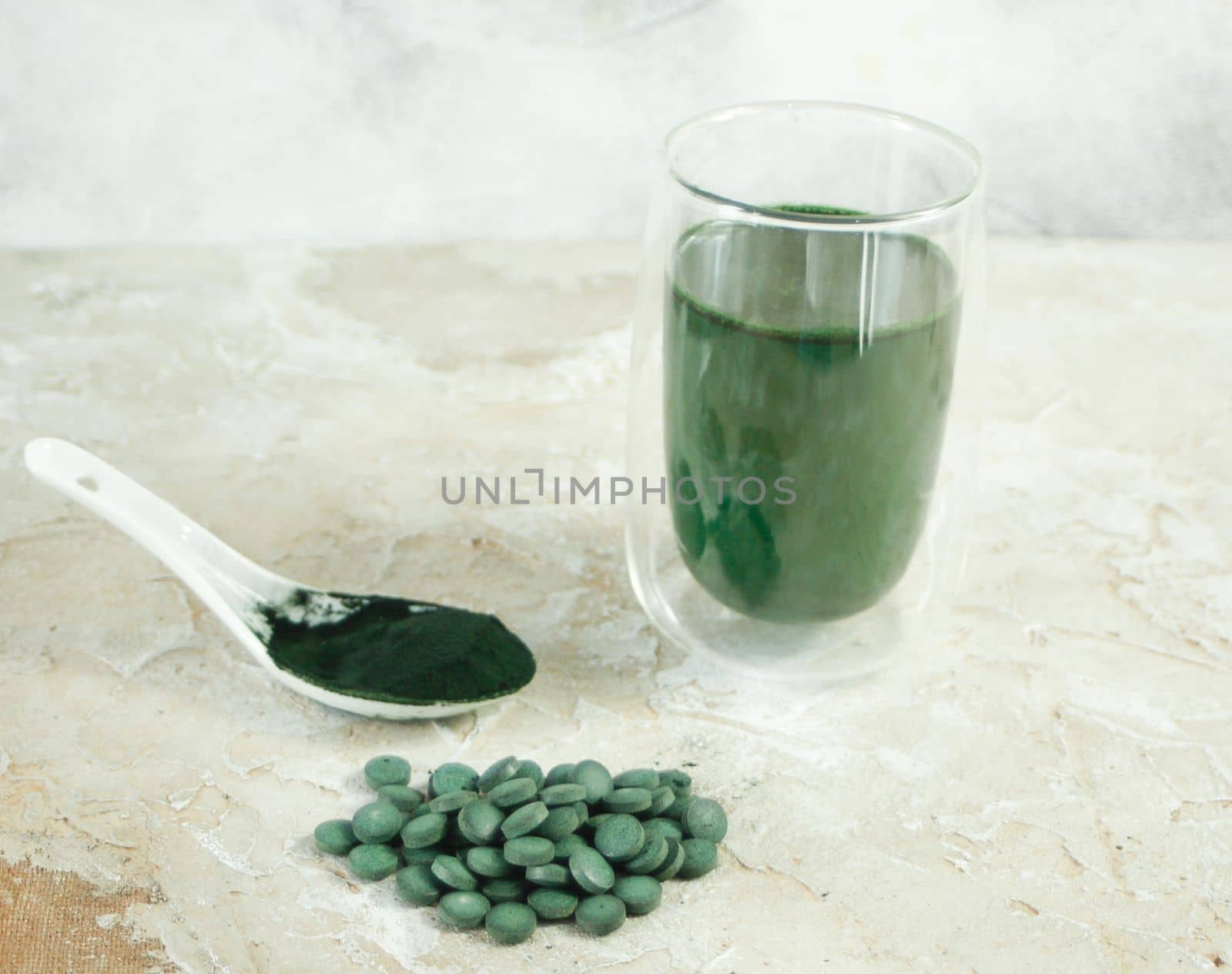 Spirulina tablets, powder and tea on concrete beige background