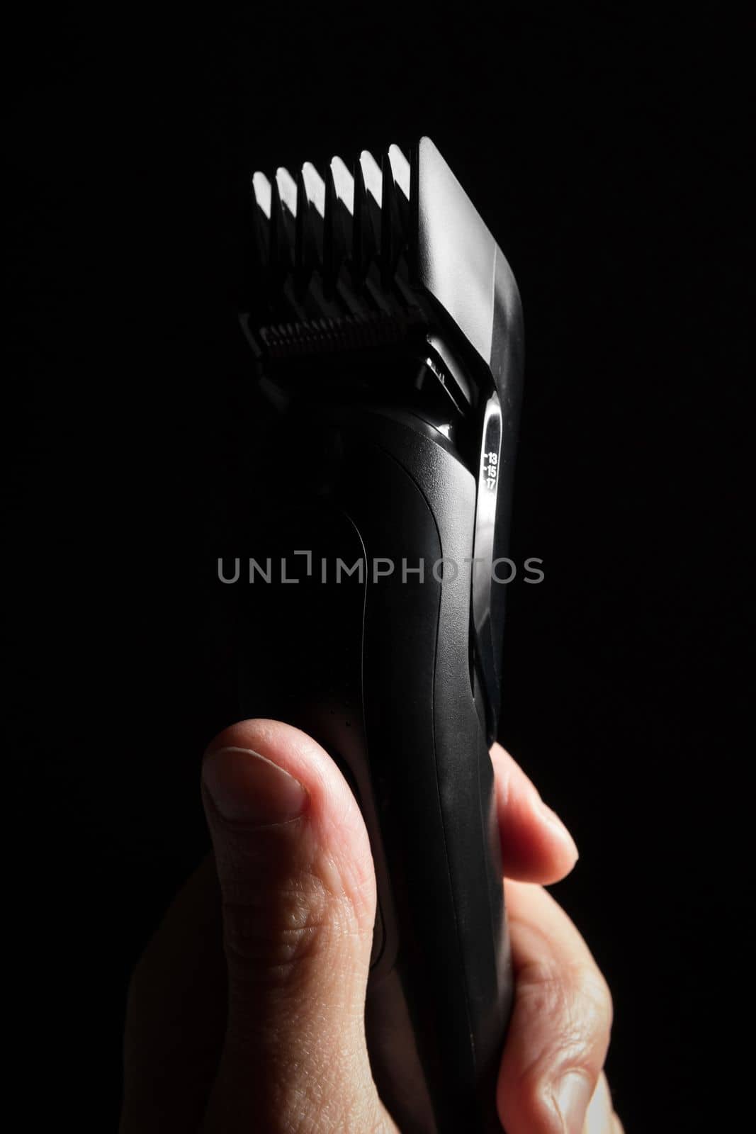 Close-up of Electric shaver machine with nozzle in hand on black background.