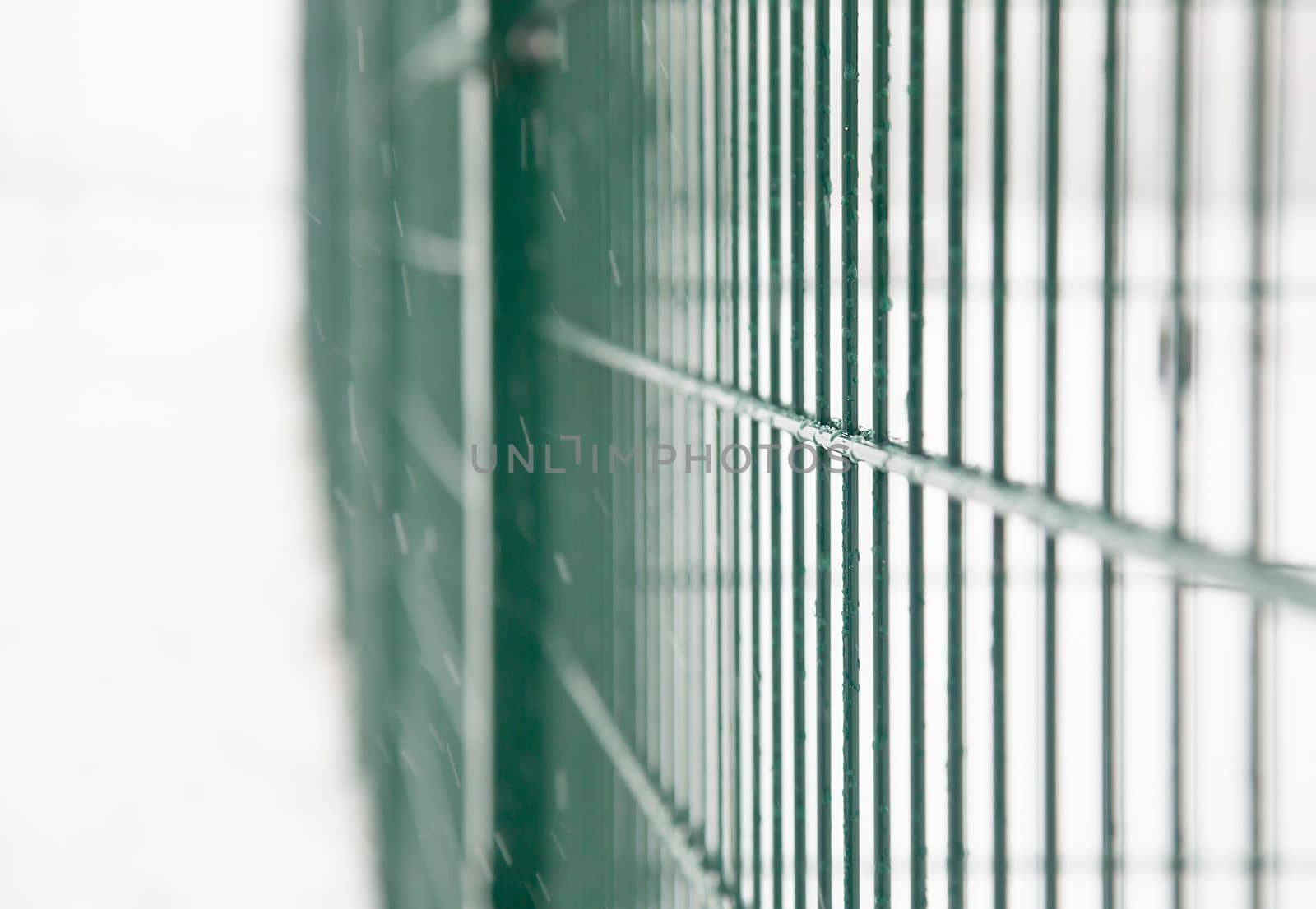 Background. Metal fence on the street in winter. Metal bars with frozen water. The icy fencing, barrier,