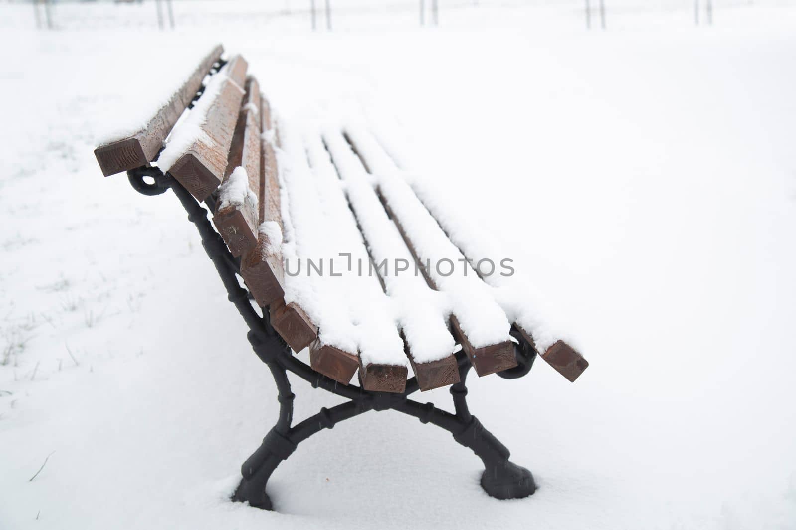 Wooden bench covered with snow. A bench in the park after a snowfall. Winter time, weather phenomenon.