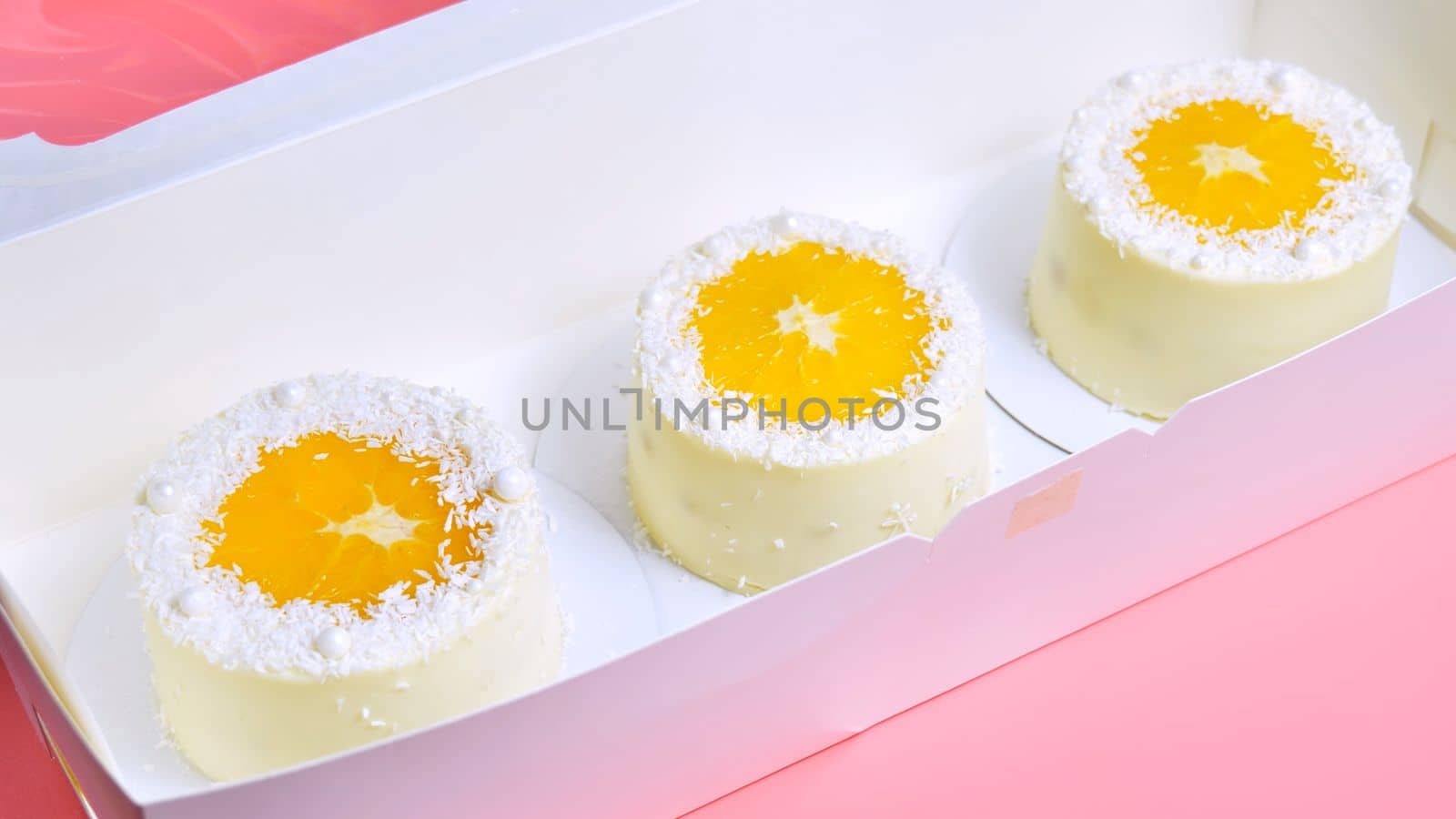 Small cakes with orange and coconut shavings in a box