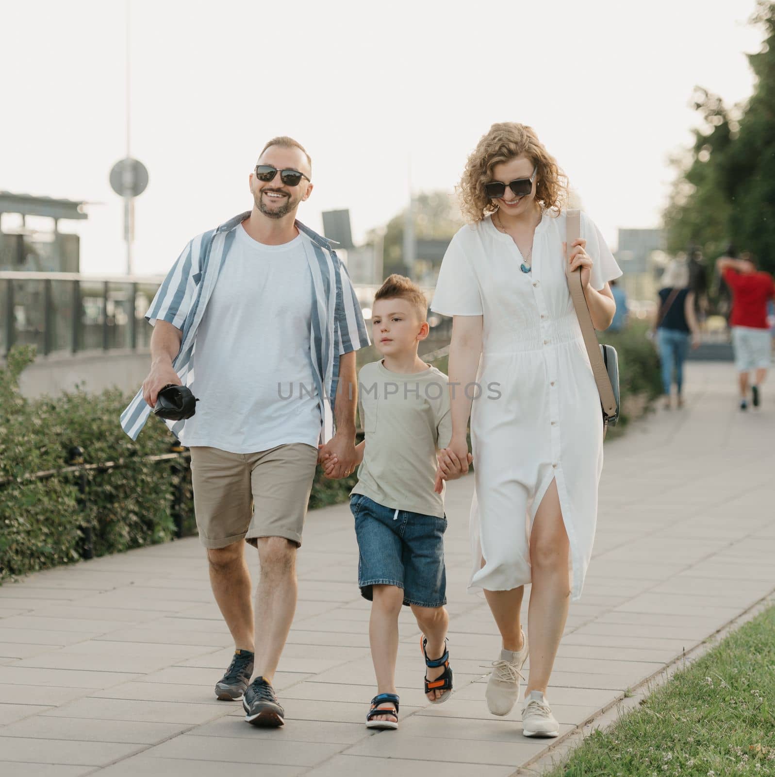 Father, mother and son are strolling down the street. Happy family in the evening.
