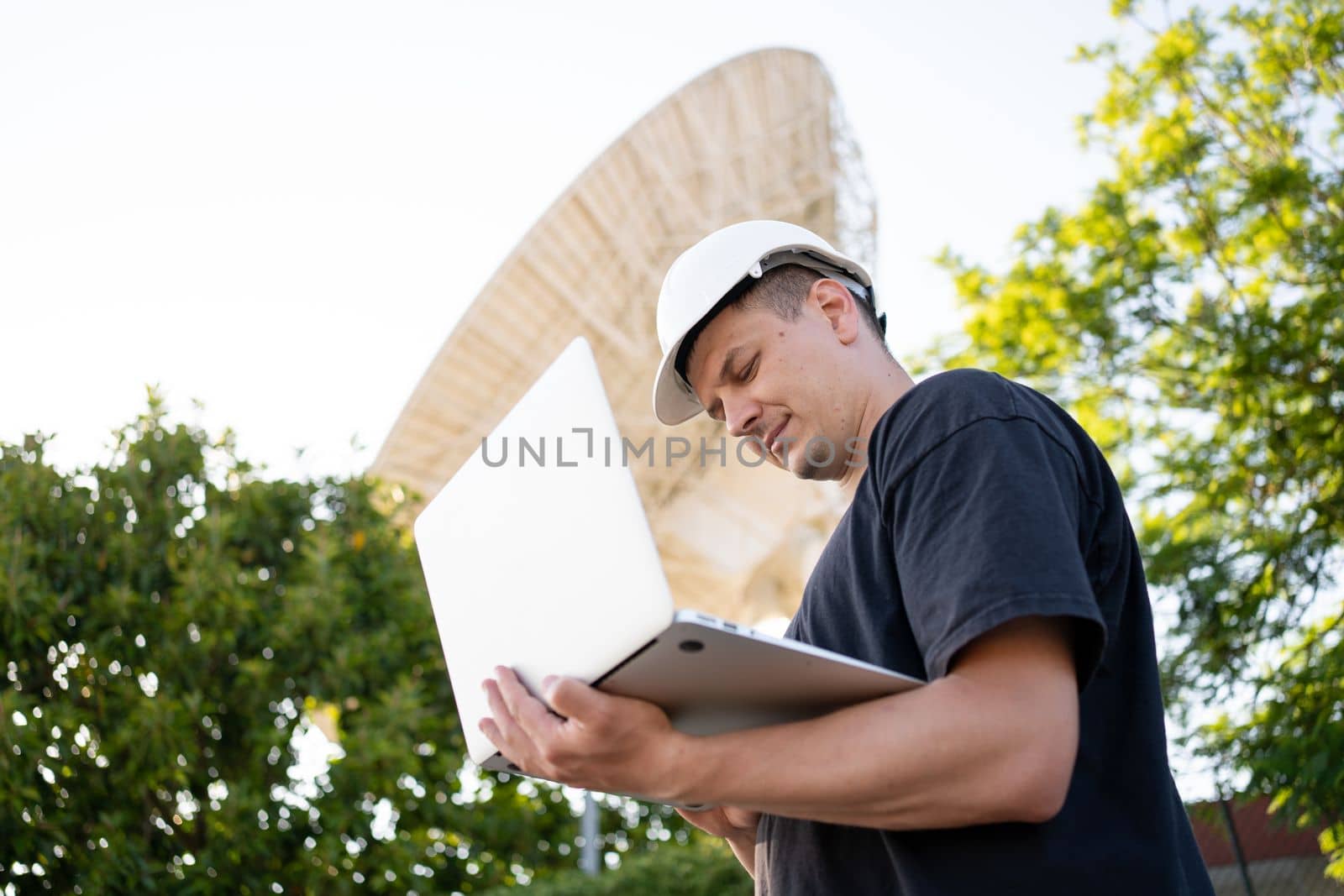 Engineer testing earth based astronomical radio telescope use laptop. Radio telescopes used in science for space observation and distant objects exploring. Big satellite dishes