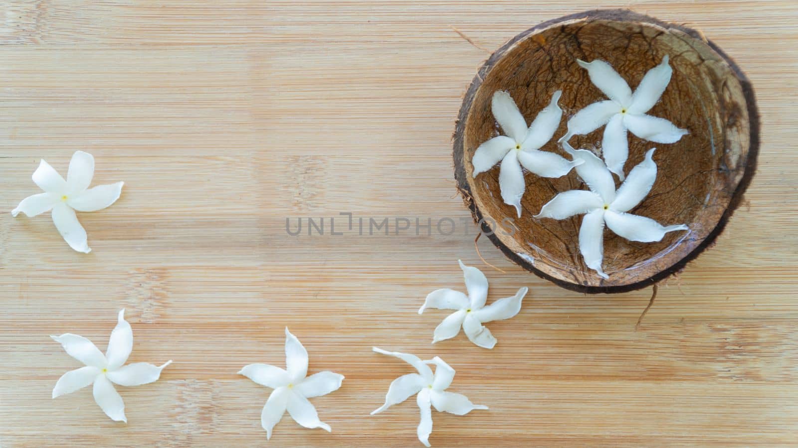 White flowers in water in a bowl of coconut on a wooden background. High quality photo