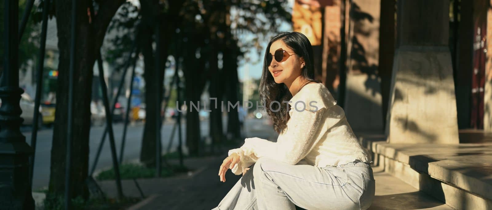 Modern millennial women in sunglasses sitting on stairs at the shopping district of a city. Banner background, panoramic view by prathanchorruangsak