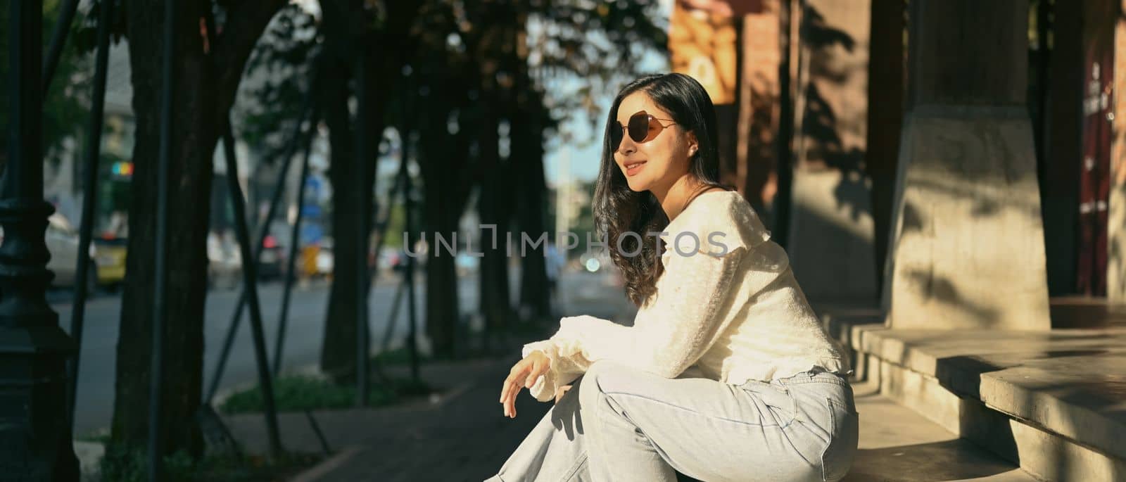 Modern millennial women in sunglasses sitting on stairs at the shopping district of a city. Banner background, panoramic view.