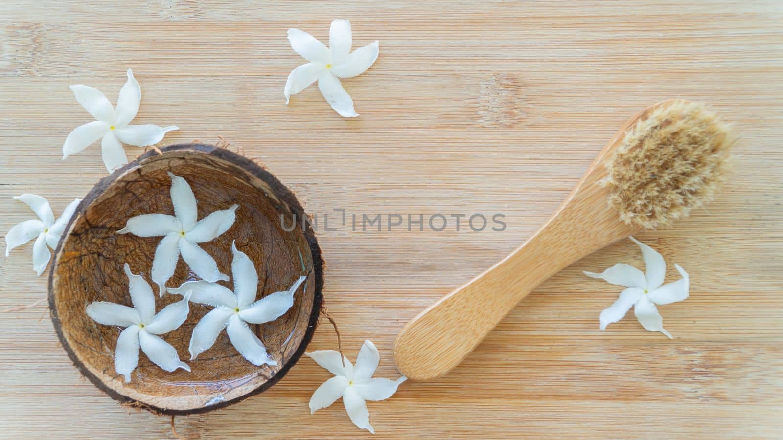 Massage brush on a wooden background with flowers, spa salon, personal care. High quality photo