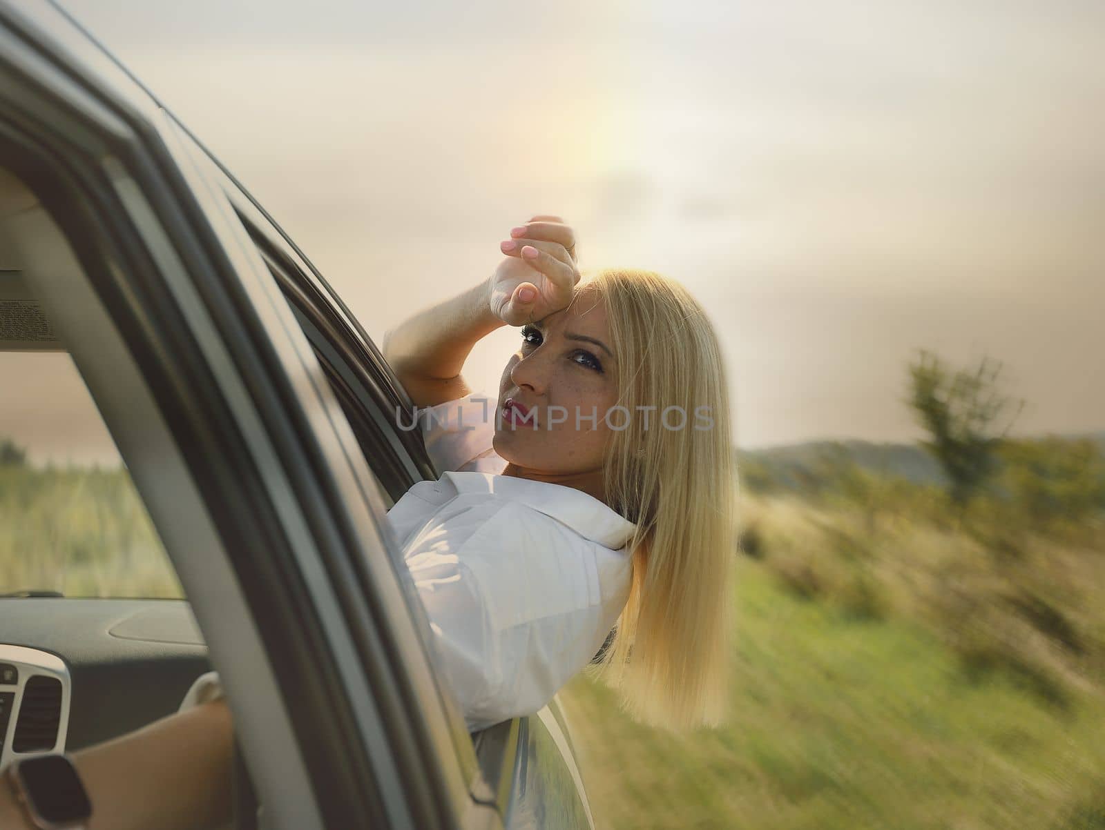 A beautiful girl rides in a car at speed and enjoys the wind from the window, rest from work and bustle, serenity and freedom. High quality photo