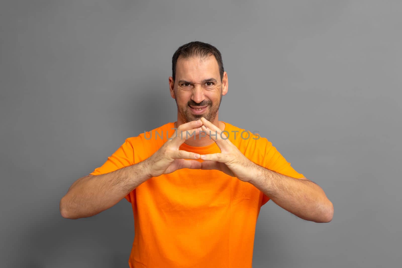 Evil genius, scheming man, making plans, looking cunning and thoughtful, mastermind idea, tipping fingers while thinking, standing against gray background