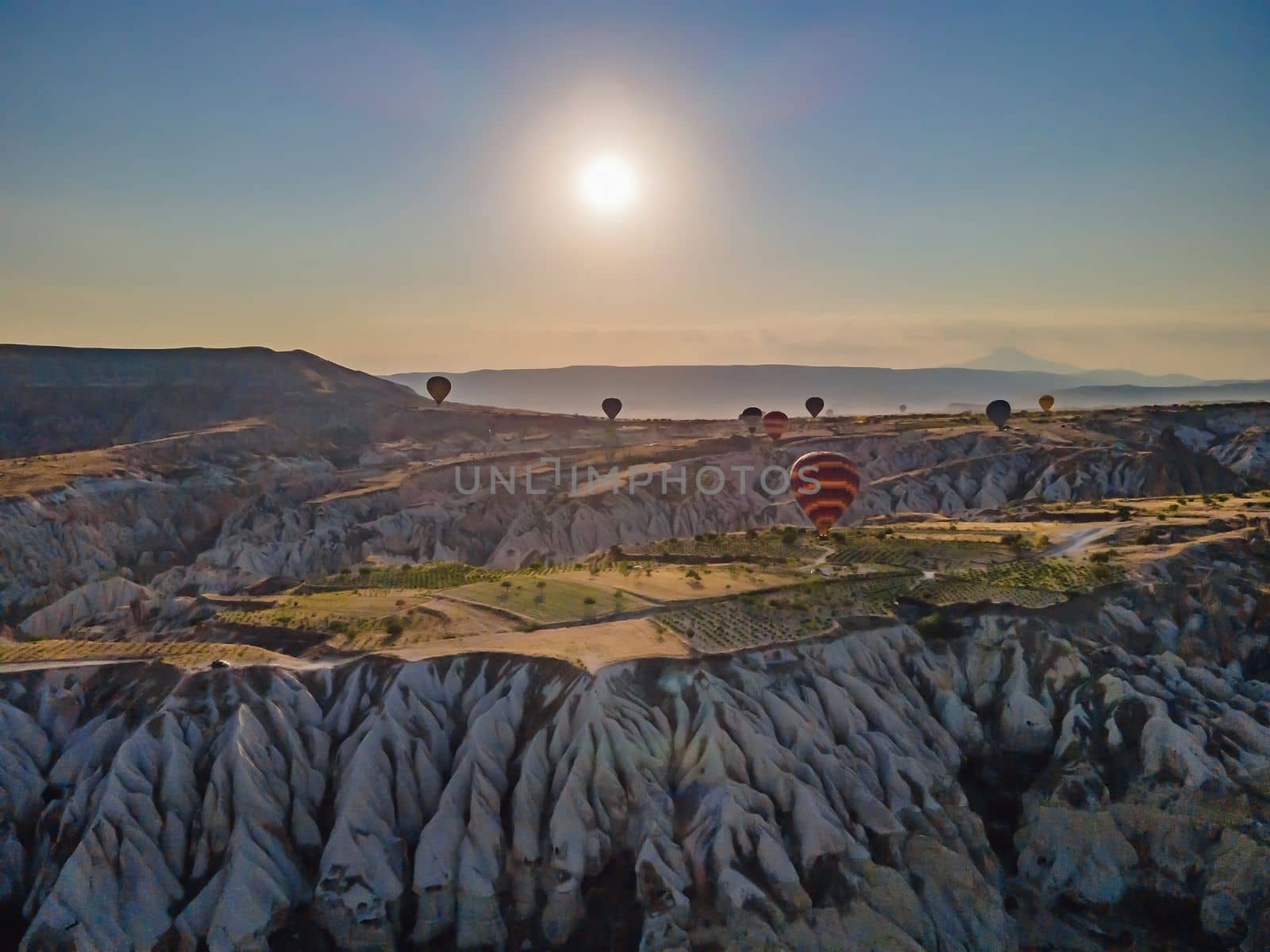 Colorful hot air balloons flying over at fairy chimneys valley in Nevsehir, Goreme, Cappadocia Turkey. Spectacular panoramic drone view of the underground city and ballooning tourism. High quality by galitskaya