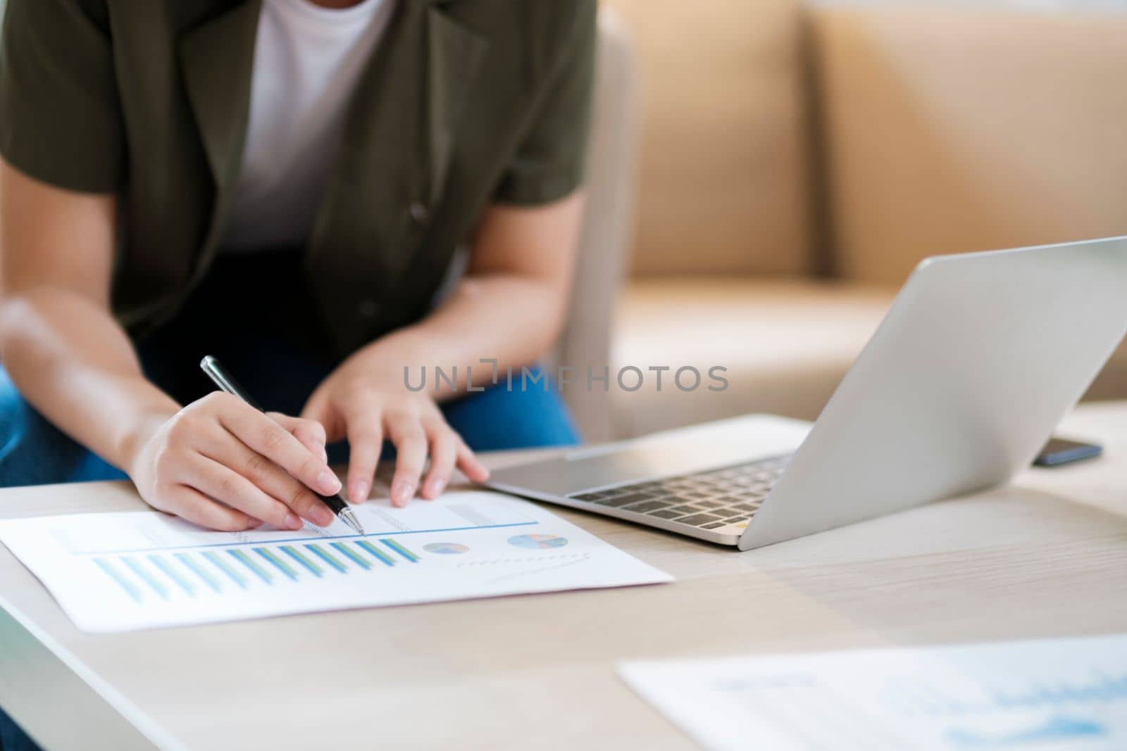 Close up of Young asian businesswoman working hard at the office using laptop data graphs, planning for improvement, analyzing and strategizing for business growth smiling at camera. Business concept.