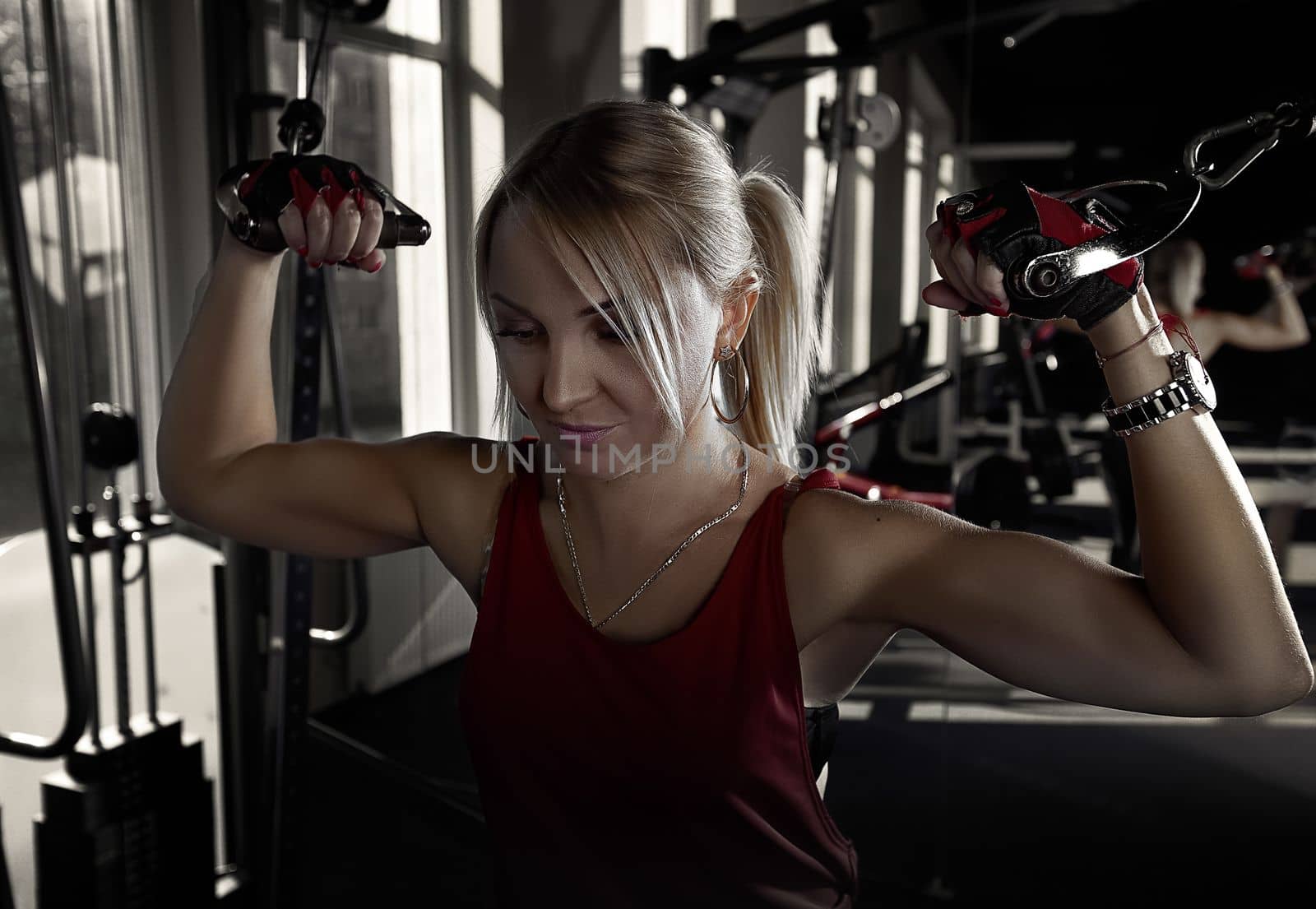 Fitness woman working out in gym doing exercise for biceps. Athletic girl training .Beautiful fitness woman lifting dumbbells . Fitness sporty woman showing her well trained body