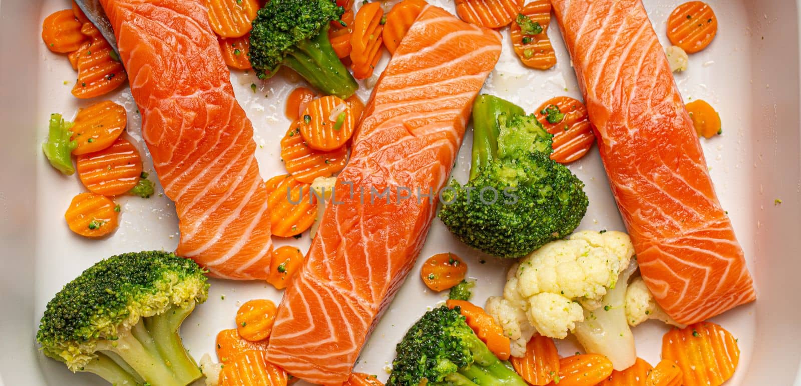 Top view of baking dish casserole with raw uncooked fish salmon steaks, broccoli, cauliflower, carrot. Preparing a healthy dinner concept by its_al_dente