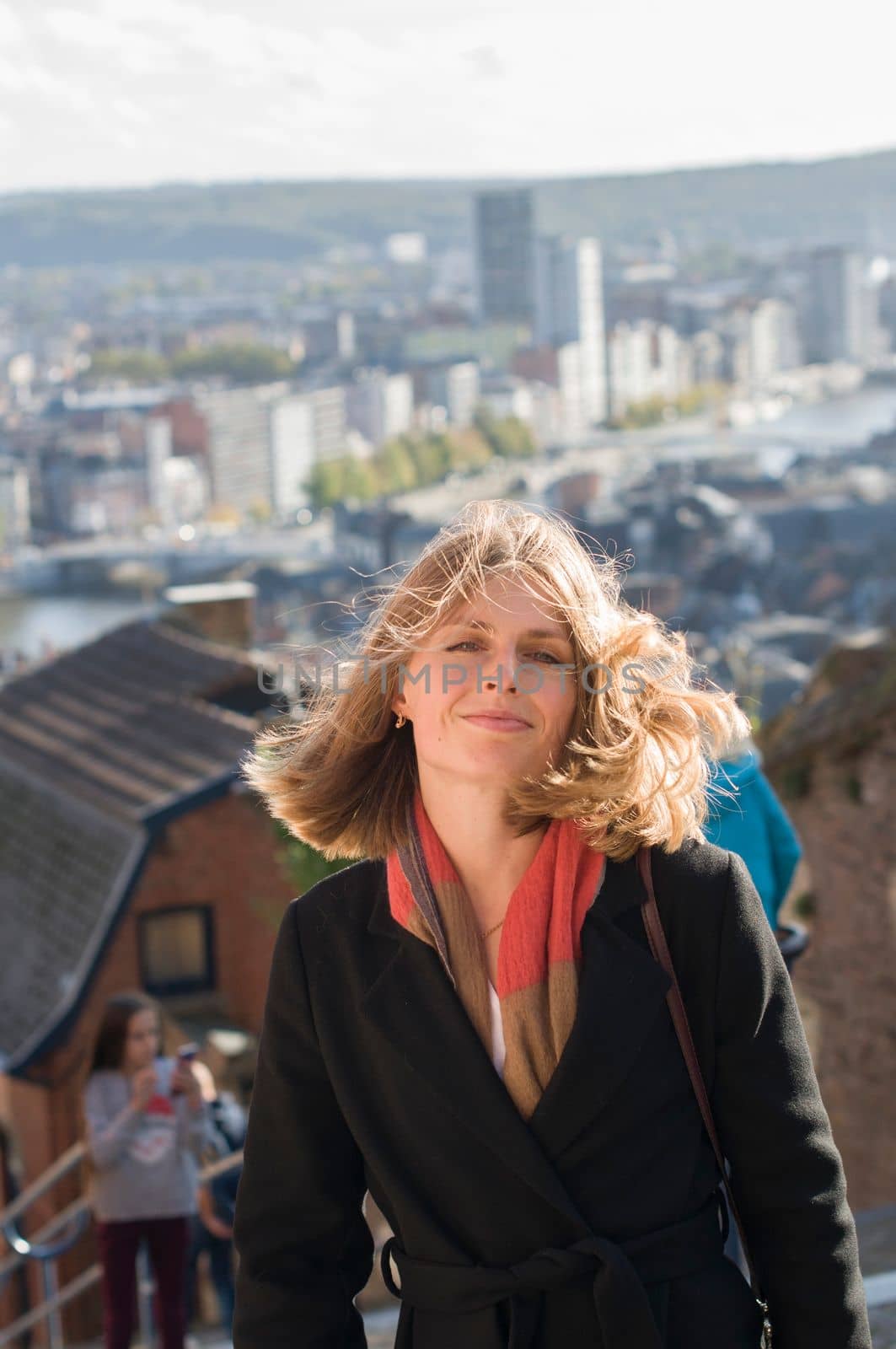 portrait of a beautiful young blonde girl with flying hair in the sun against the backdrop of a big city. High quality photo