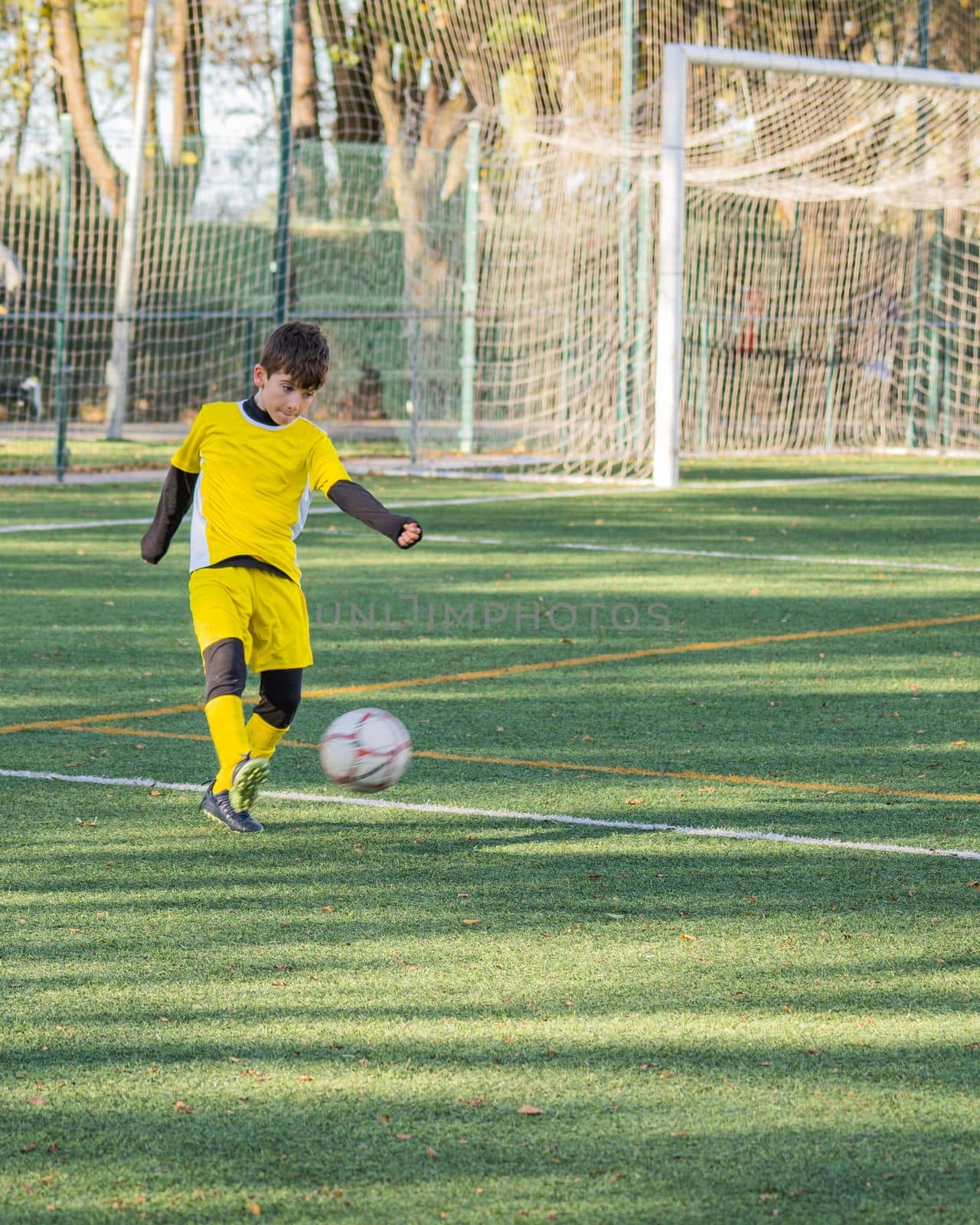 Football player in yellow uniform shooting the ball during a match.