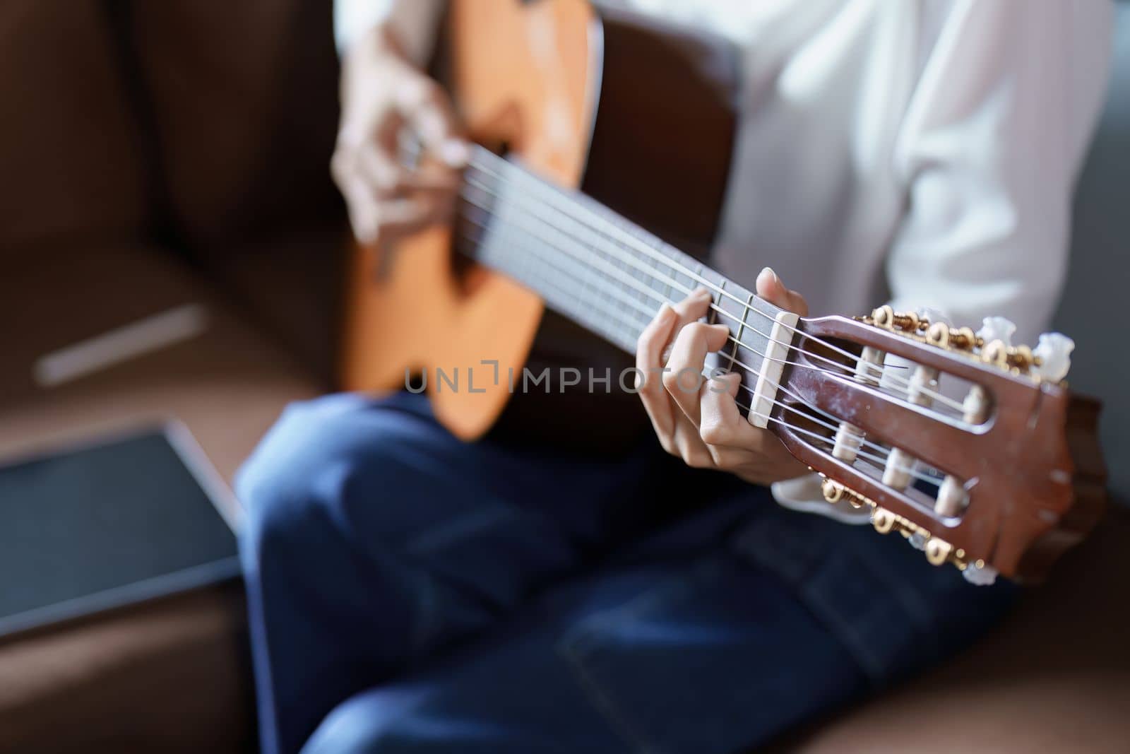 Portrait of young asian woman playing guitar on sofa relaxing stress on vacation.