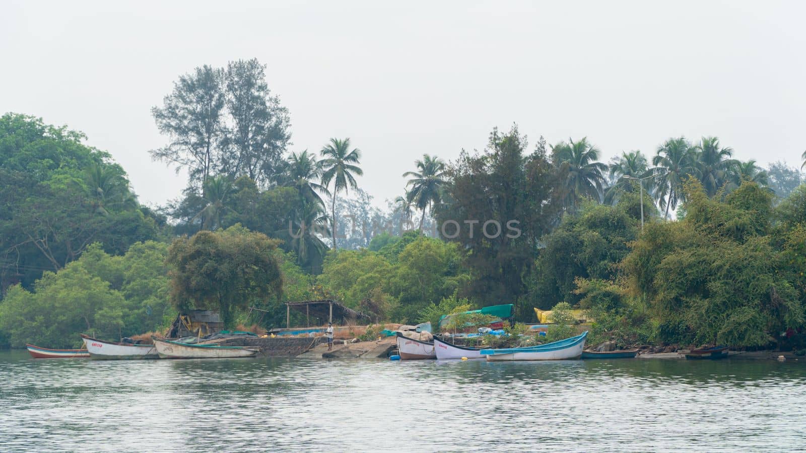 Fishing boats on the river against the backdrop of palm trees on a foggy morning by voktybre