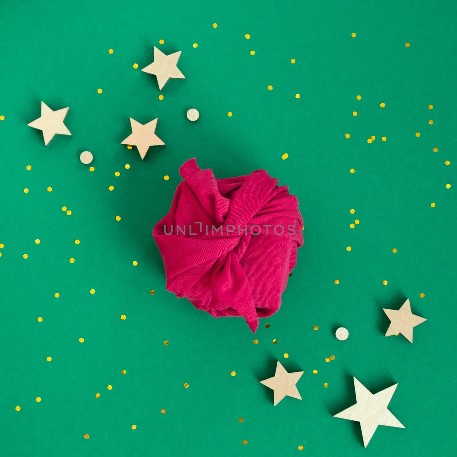 Paper free gift wrapping technique Furoshiki. Viva magenta fabric on green background. Flat lay, present box, top view. Christmas, valentines, new year concept