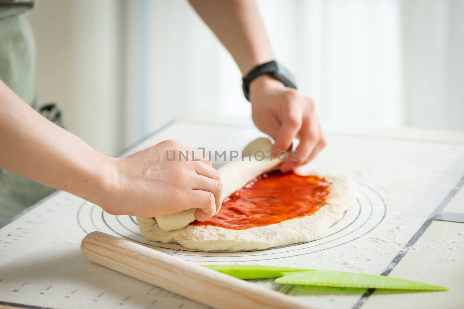 The cook is cooking a sweet roll with strawberry jam on a white silicone baking mat.
