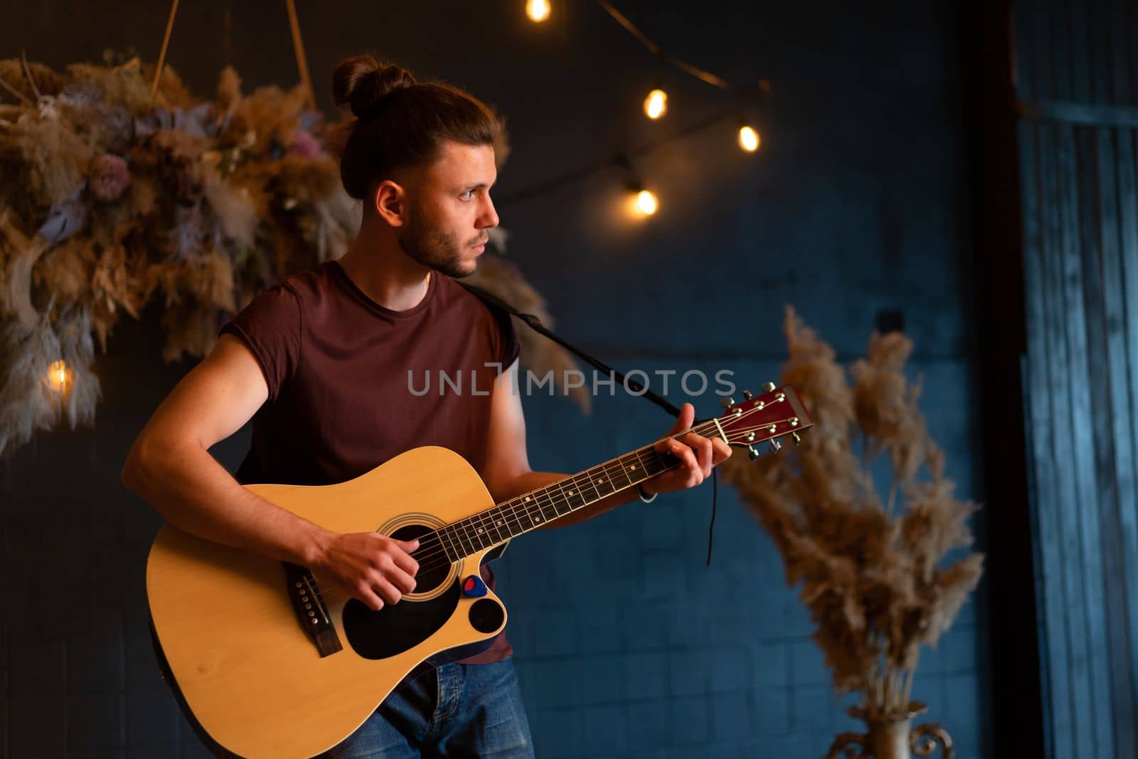 Male musician playing acoustic guitar. Guitarist plays classical guitar on stage in concert Handsome young hipster male guitar player perform private party Stylish long hair Medium shoot