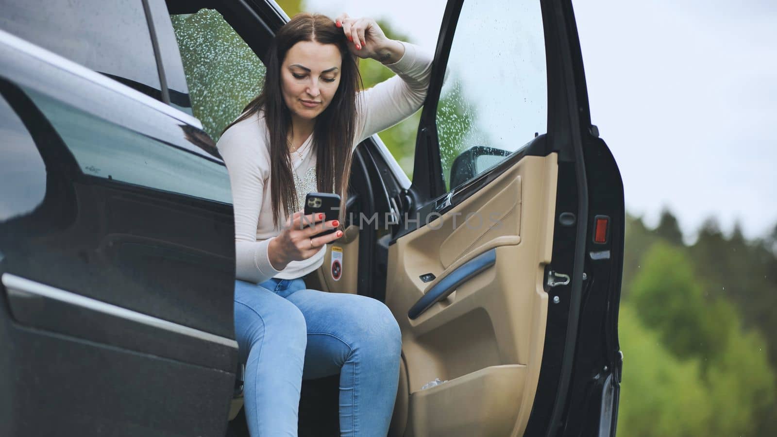 A girl is looking through her phone while sitting in her car