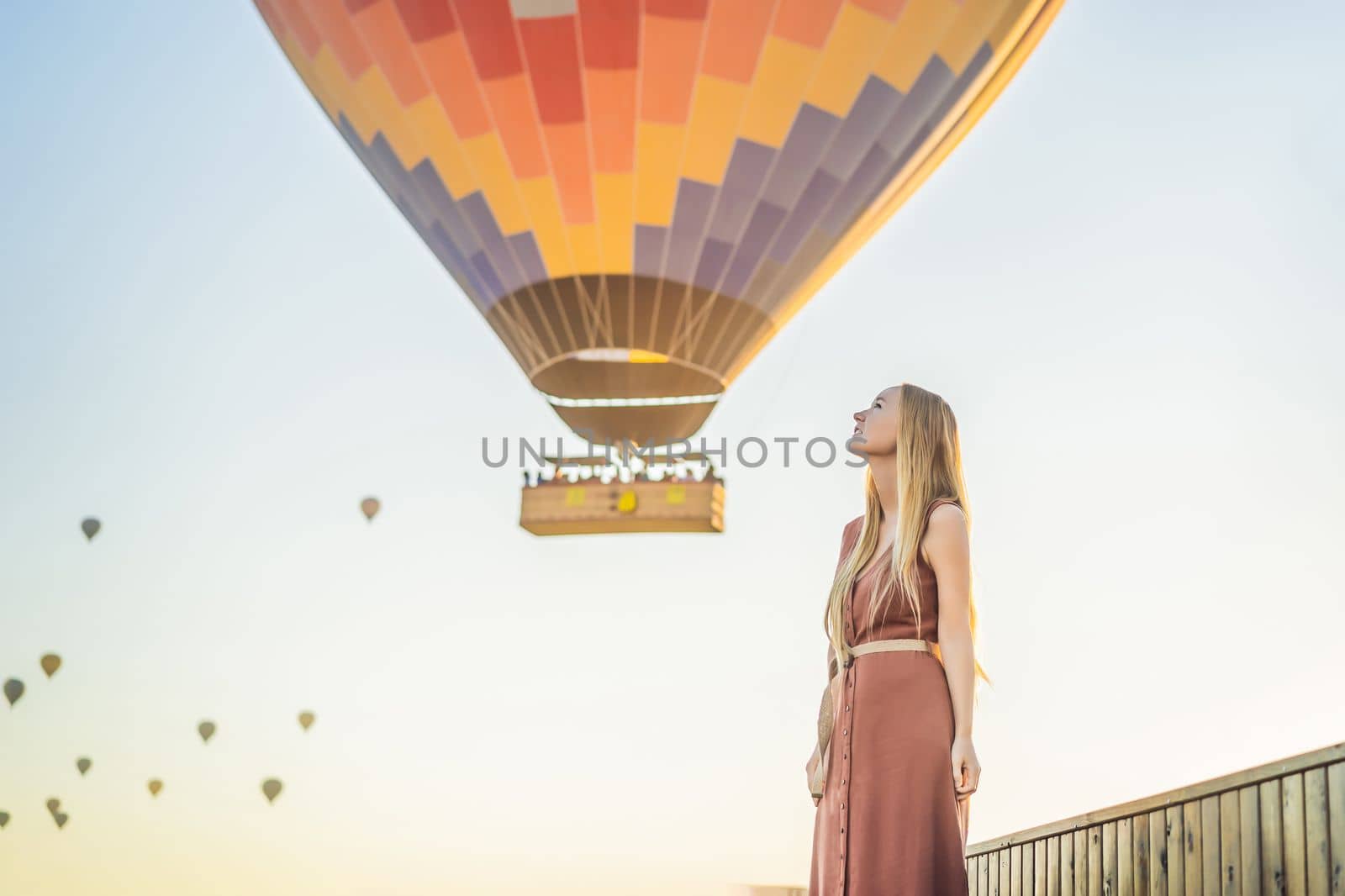 Tourist woman looking at hot air balloons in Cappadocia, Turkey. Happy Travel in Turkey concept. Woman on a mountain top enjoying wonderful view.