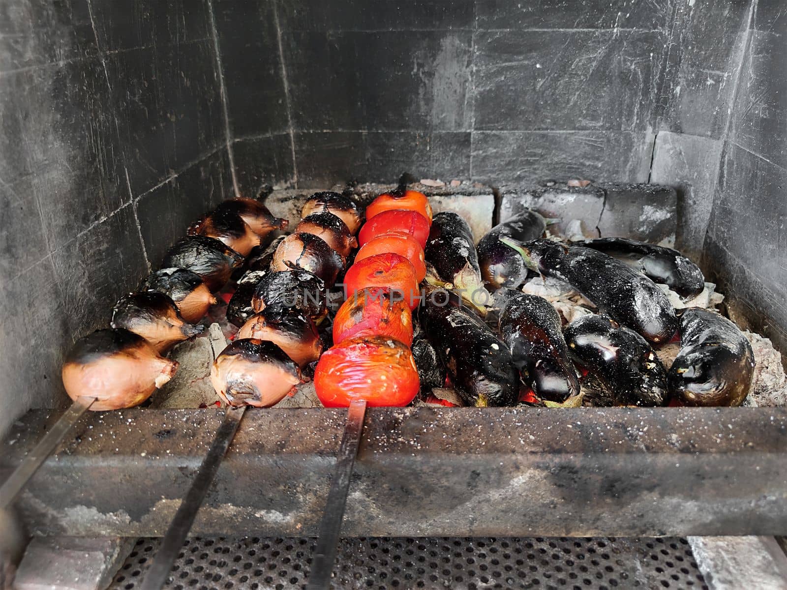 Vegetables on skewers are fried on coals. Onions, tomatoes, grilled eggplant. Picnic