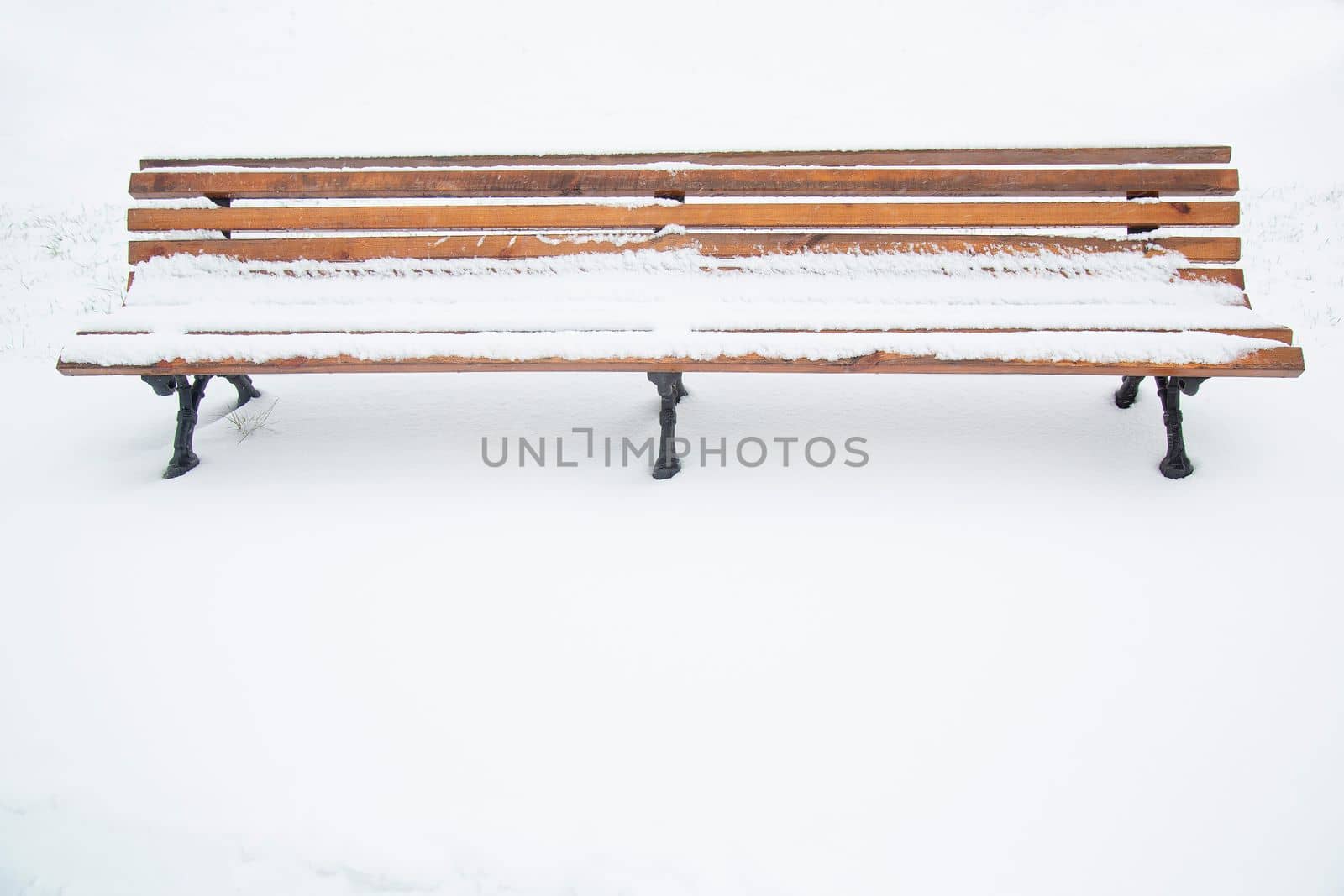On a winter day in the park. Wooden bench covered with snow. A bench in the park after a snowfall. Winter time, weather phenomenon.