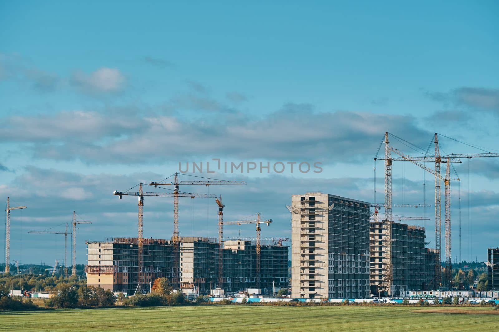 Industrial building cranes and multi-storey houses for relocation. Construction of new urban district. Blue sky with clouds.