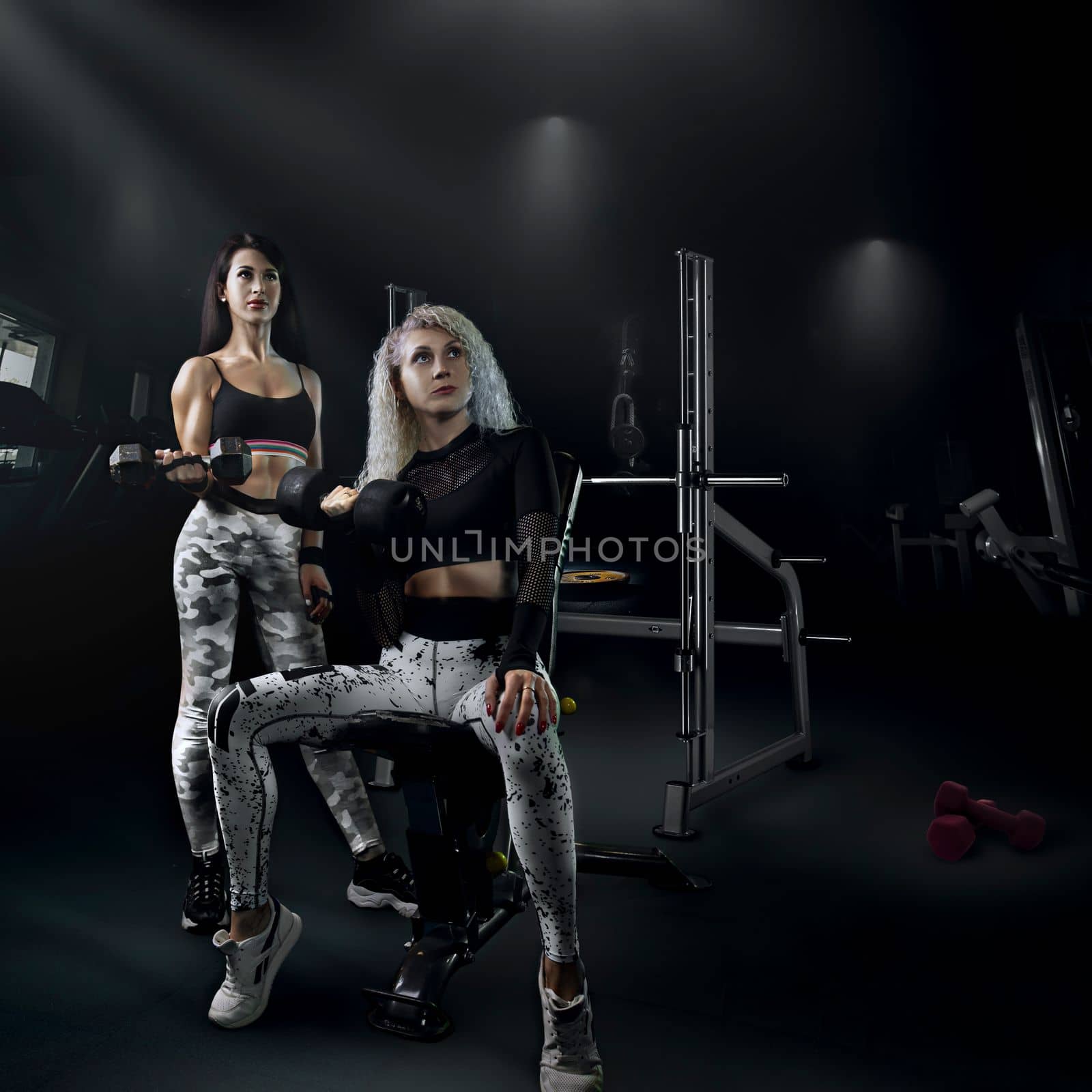fitness bodybuilding a couple of beautiful girls do sports together with a trainer with a beautiful body and a slim figure pose in the gym, creative photo. High quality photo