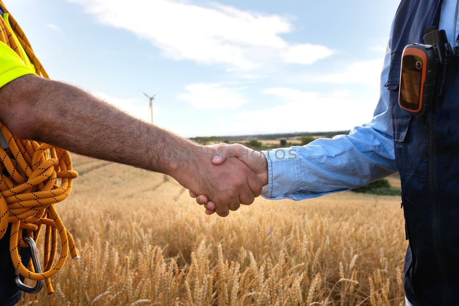 Close up of electric engineer and maintenance worker handshake in wind turbine farm. by Hoverstock