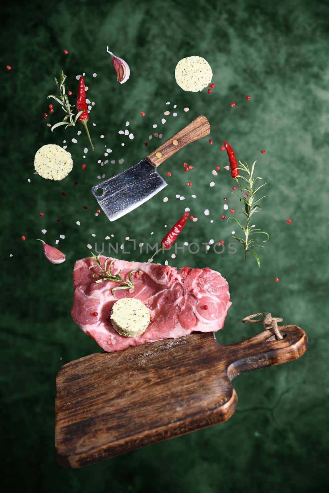 Art photo levitation of a meat steak with ingredients for frying oil spices rosemary pepper garlic on a green background. High quality photo