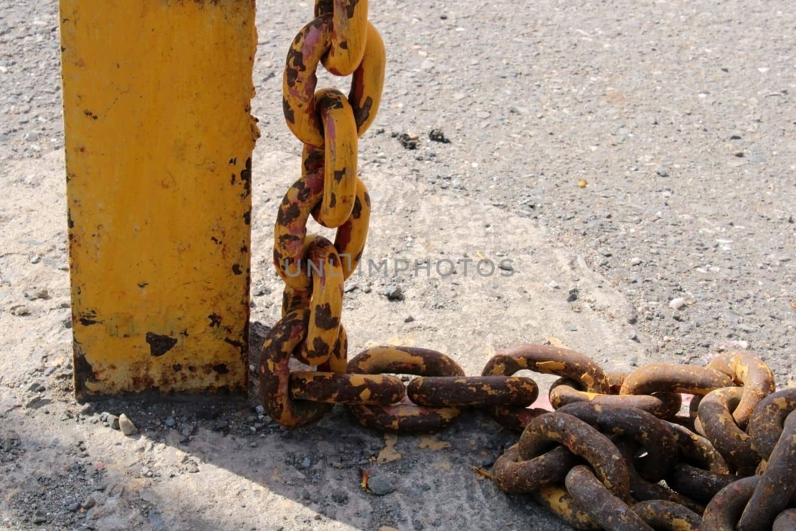 Old rusty yellow chain with large links close-up on a rack on the dock.