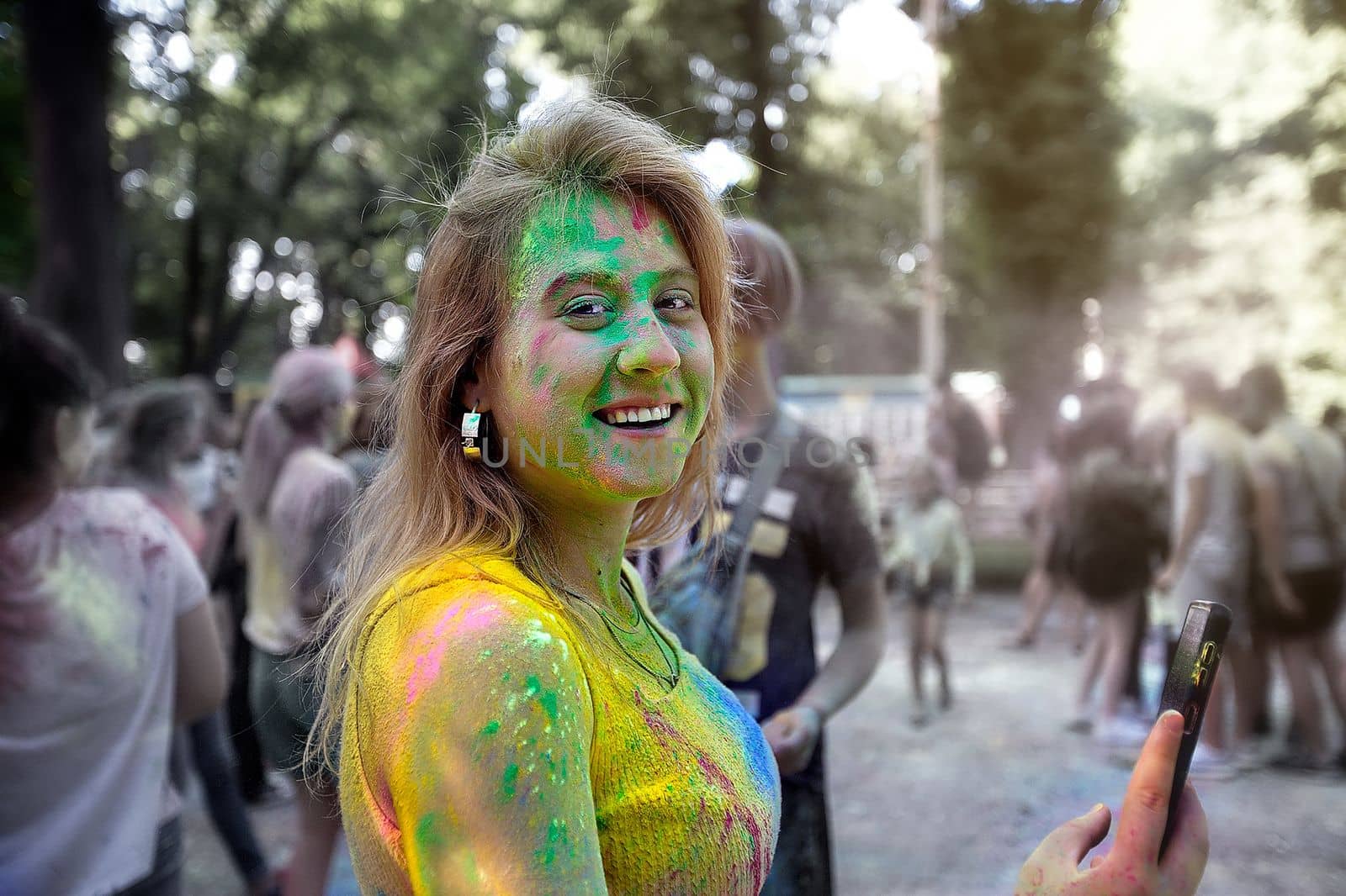 Young people, teenagers and adults celebrate the Holi event in Ukraine in Chernivtsi on March 8 in 2022. They have fun and throw paint at each other. High quality photo