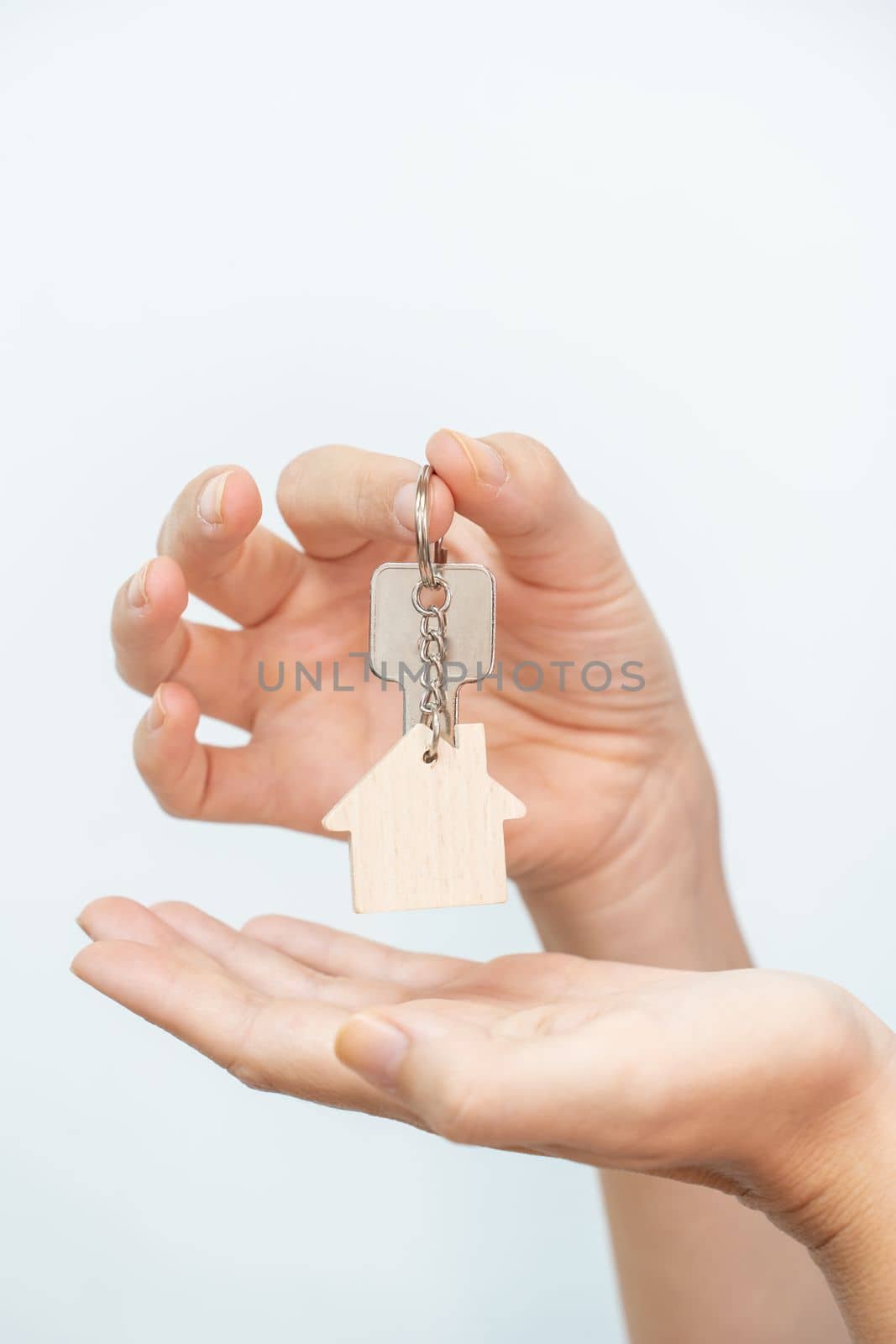 Hands holding house key on white background closeup - real state moving relocation concept by PaulCarr