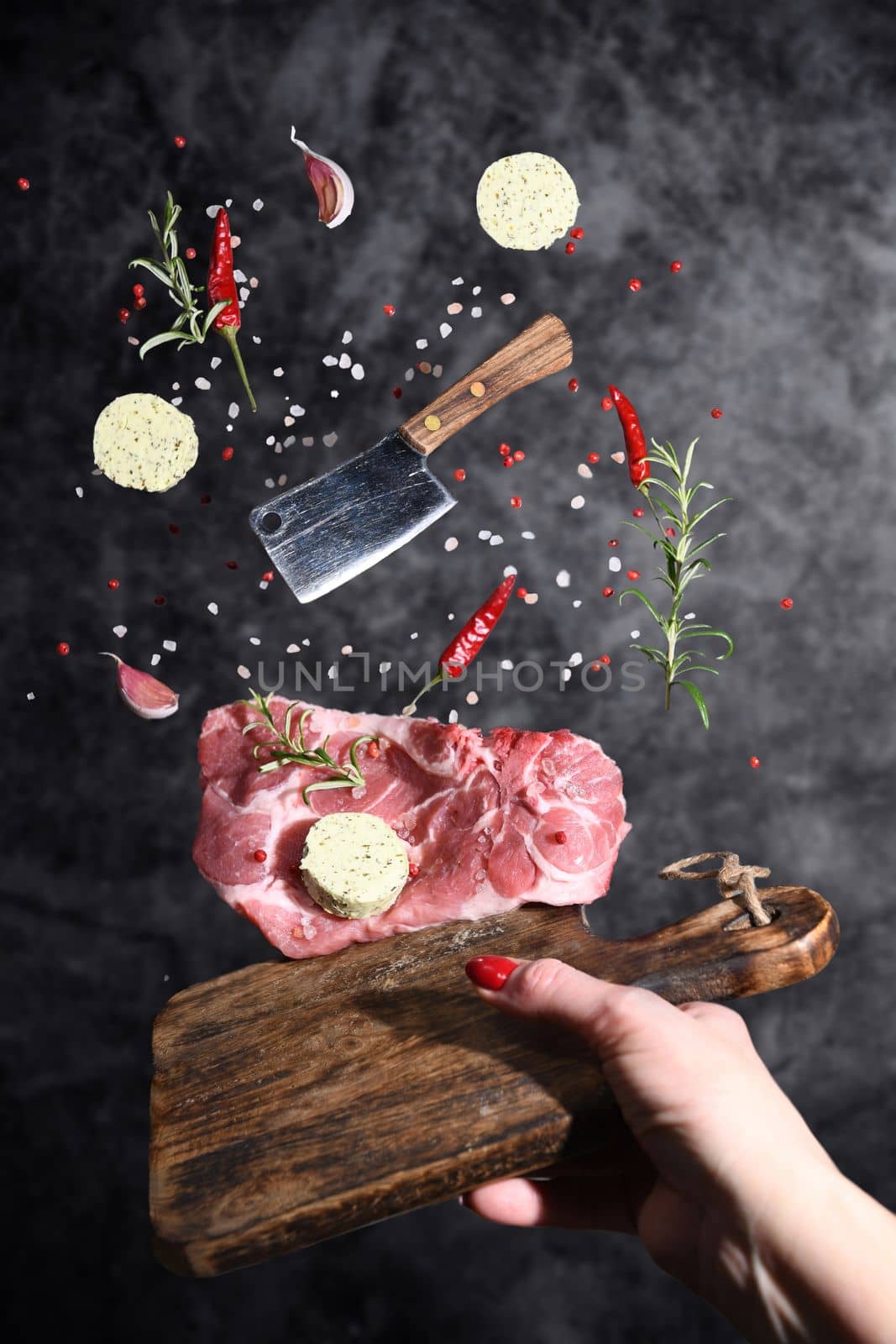 Art photo levitation of a meat steak with ingredients for frying oil spices rosemary pepper garlic on a gray background. High quality photo