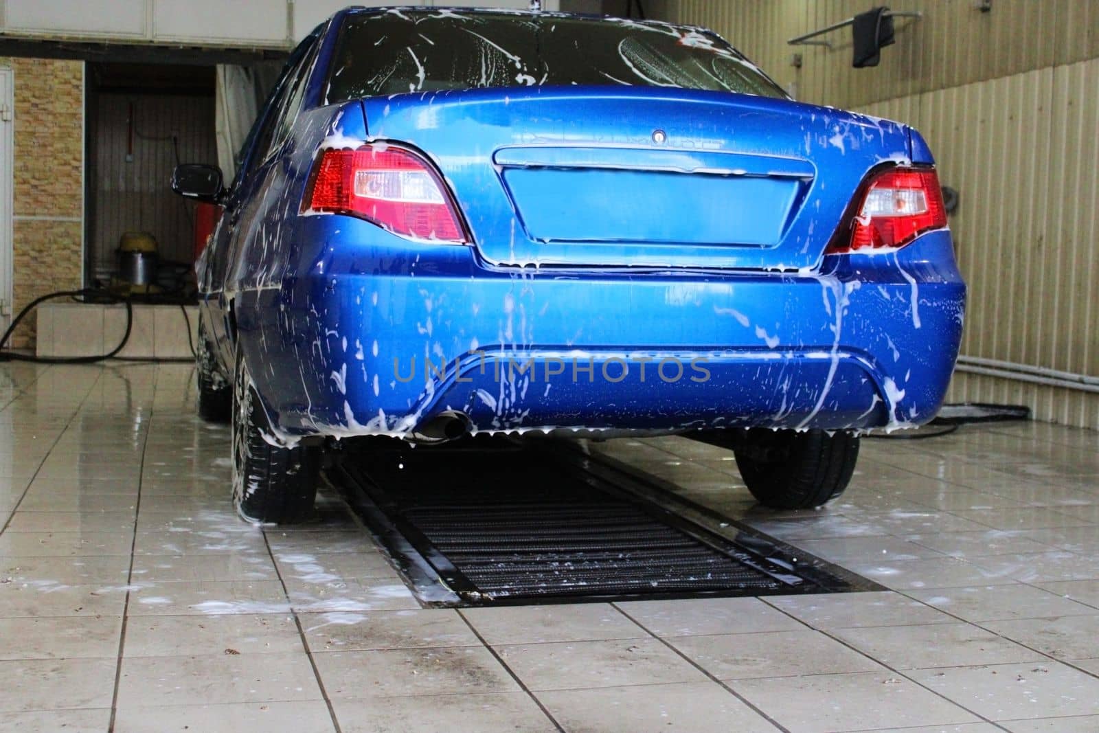 Blue car close-up at the car wash. Conception of ecology and environmental pollution by IronG96