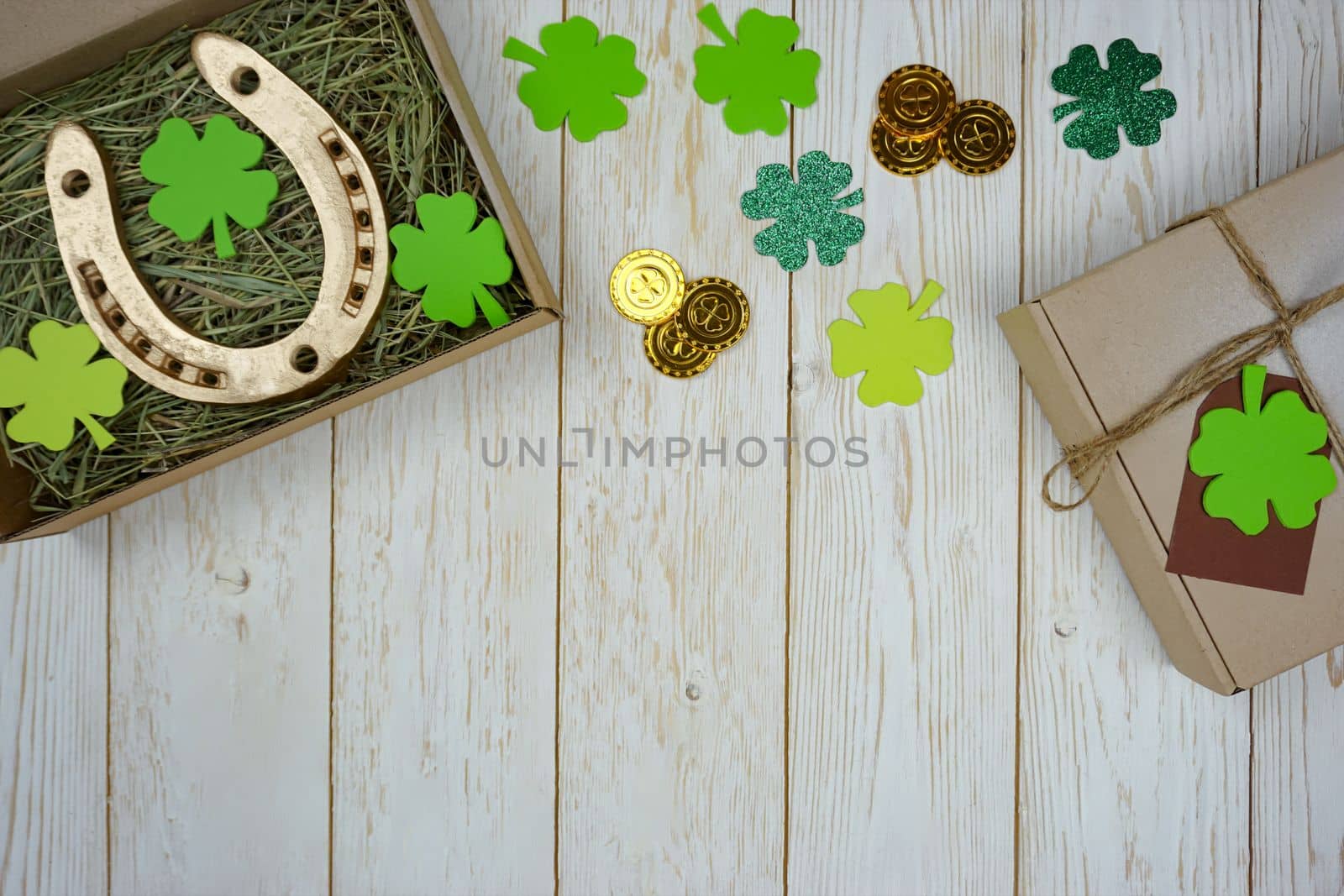 Items for St. Patrick's Day are laid out on a wooden background. Gifts for the celebration of St. Patrick. The horseshoe is in a box with fresh hay.