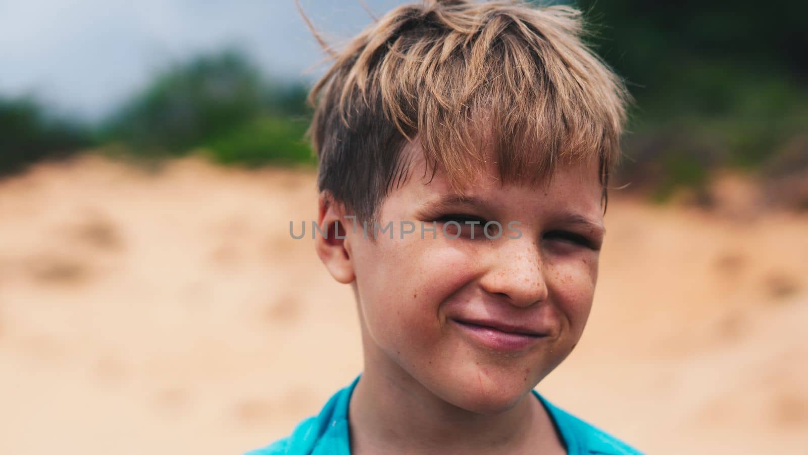 Close up portrait Boy blond freckles smile fun cunning facial expression wrinkle bright sun charming nature.