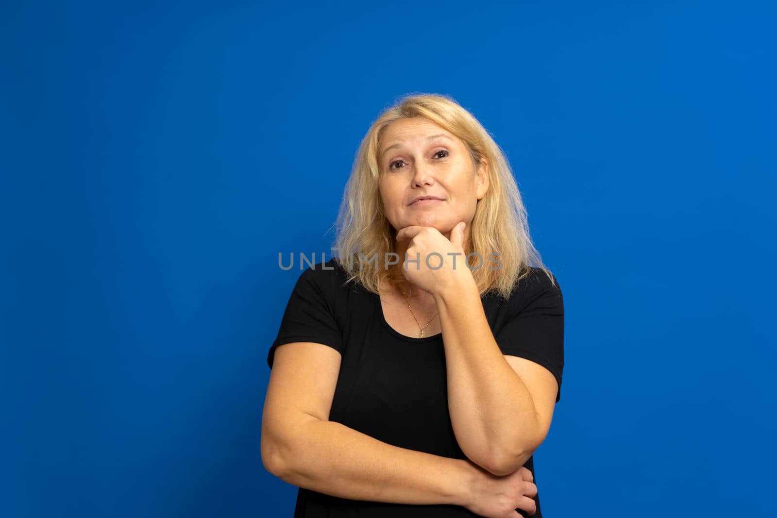 Closeup photo of amazing lady looking up into empty space, thinking deeply, creative person, arm on chin, black casual clothes, isolated blue color background